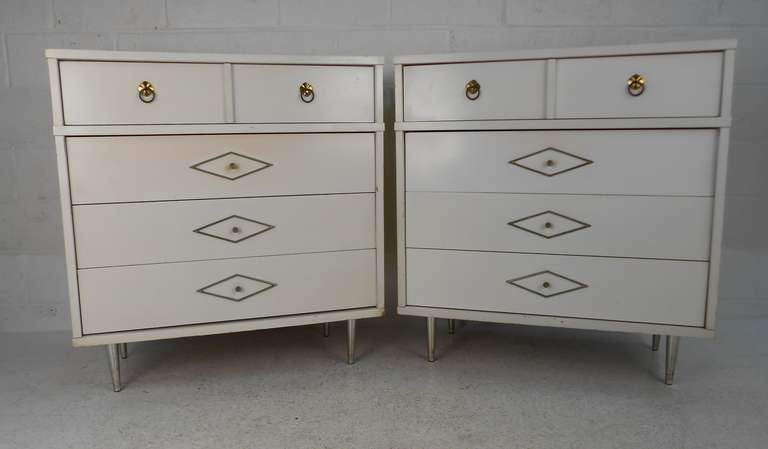 Matching pair of mid-century four-drawer dressers make a stylish addition to any interior. Unique gold trim, brass finish hardware, and tapered legs add to the appeal. Please confirm item location (NY or NJ) with dealer.