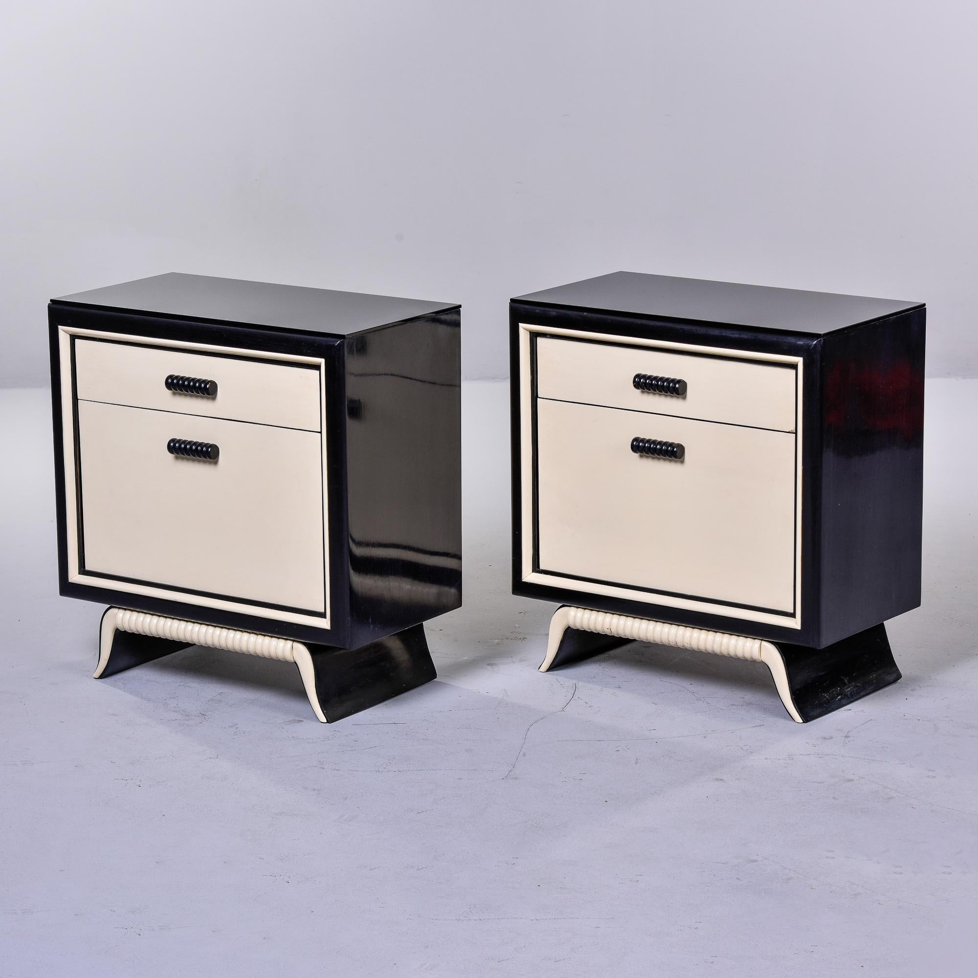 Found in Italy, this pair of circa 1950s bedside cabinets feature a black and cream painted finish. Each cabinet has a functional top drawer over a lower storage compartment with a pull down door. Curvy pedestal base has carved textured details with