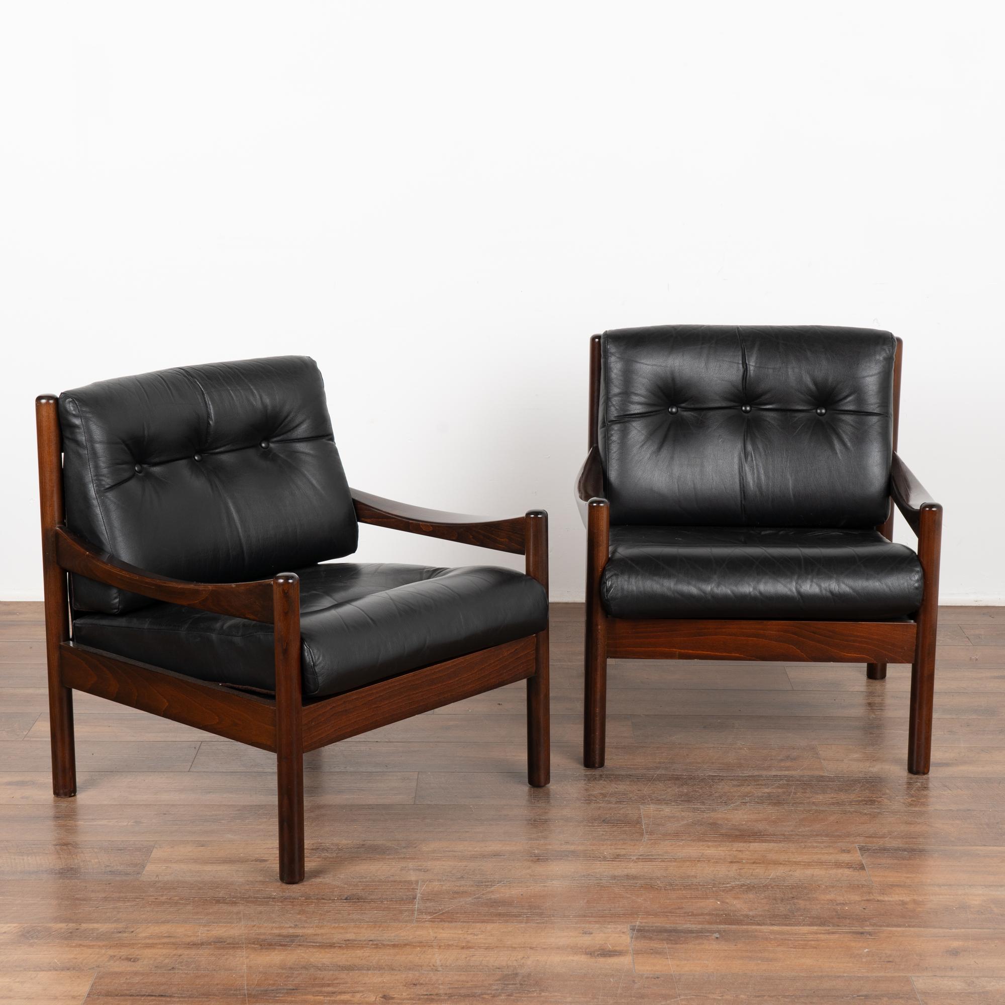 Pair, mid-century modern black leather arm chairs with tufted back and seat, three buttons in place on each.
Clean modern design with hardwood frame, these chairs sit low and comfortable.
Sold in solid, vintage used condition. Frame and leather