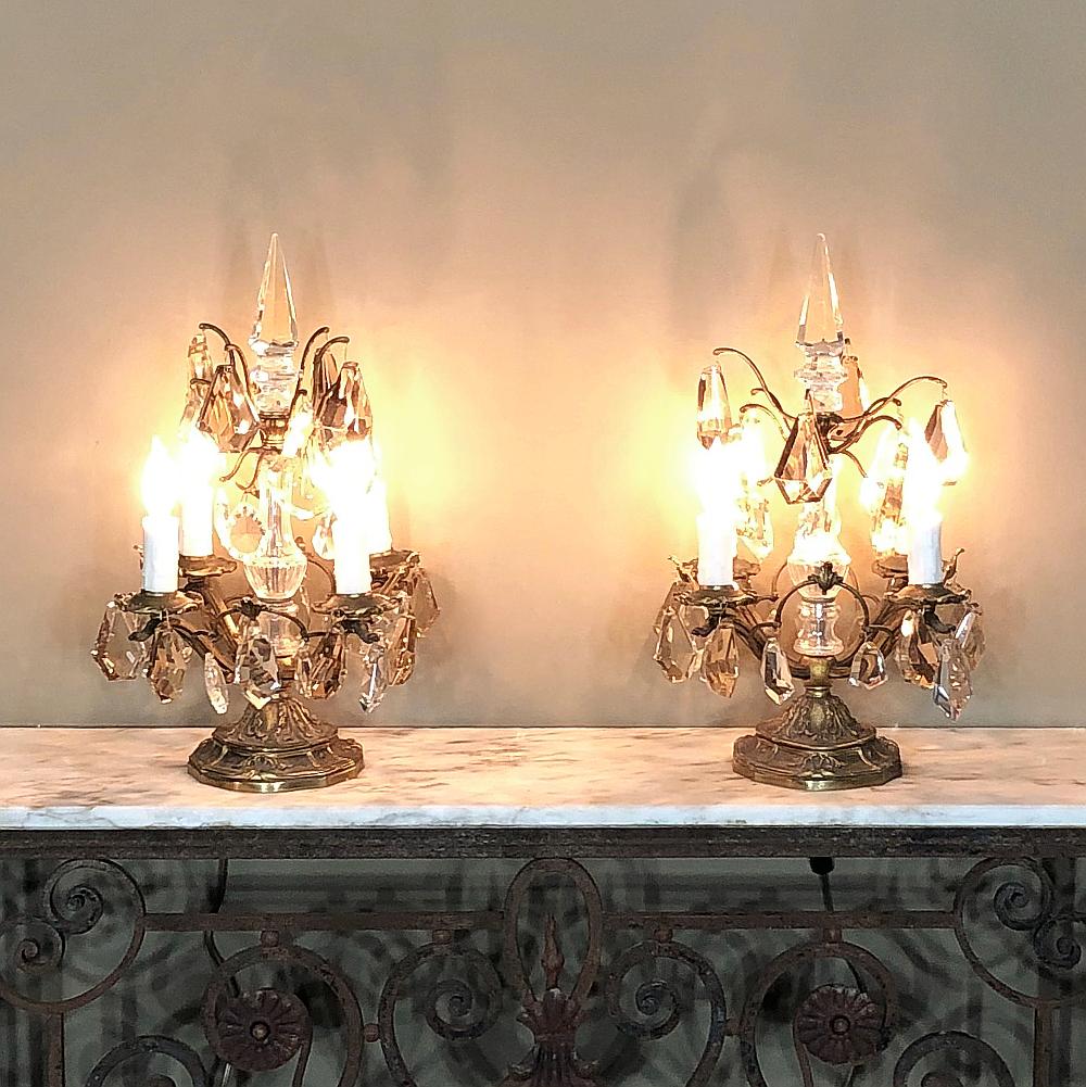 Pair of midcentury brass and crystal neoclassical girandoles or sconces features timeless styling, and intricate detail with solid brass quality enhanced by faceted crystals that play with the light and provide a source of warm ambiance. Designed to