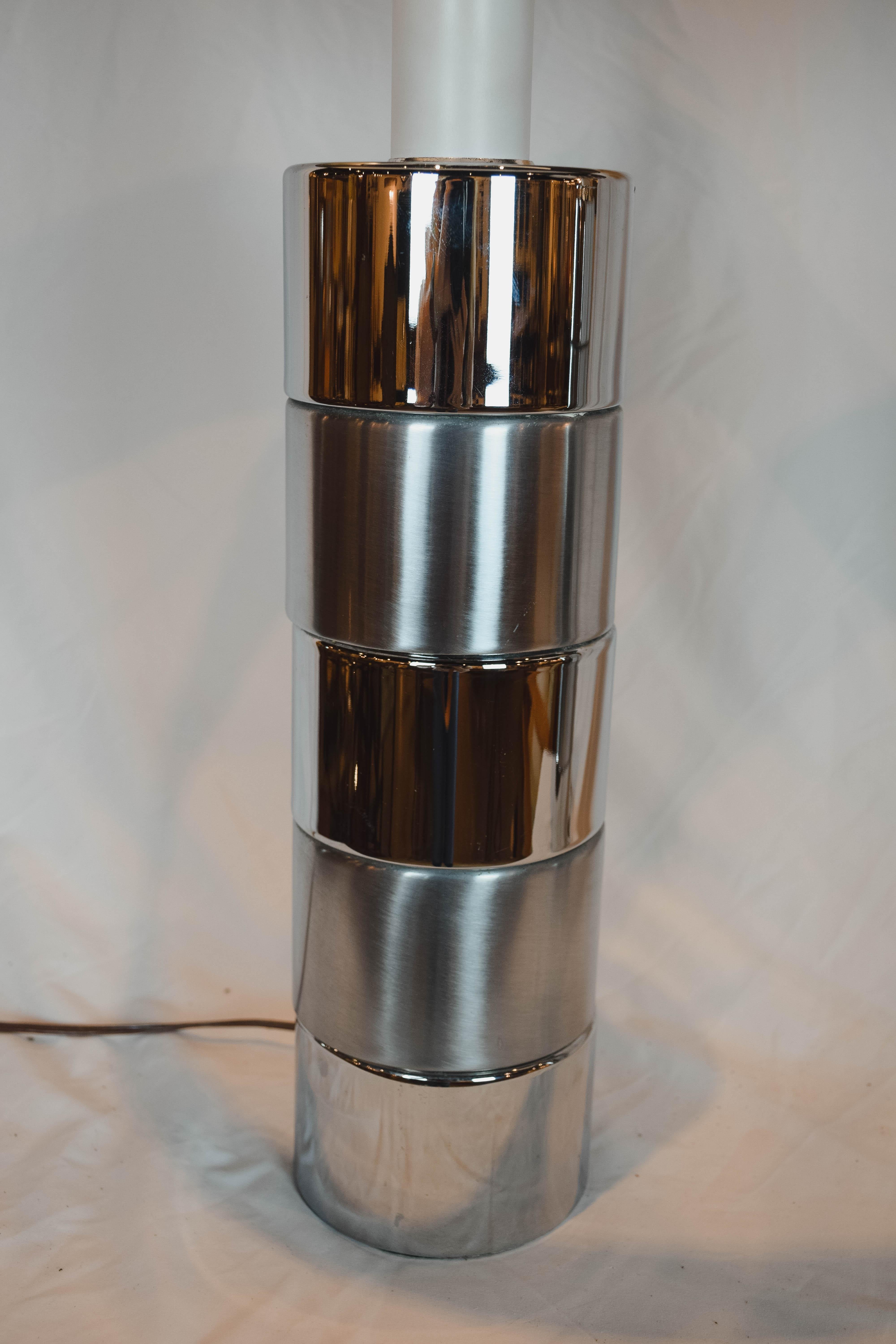 This sleek pair of midcentury chrome table lamps feature an alternating stacked cylinder chrome and brushed chrome base. The black shades add to the style of the lamps. Each lamp measures: 29.5