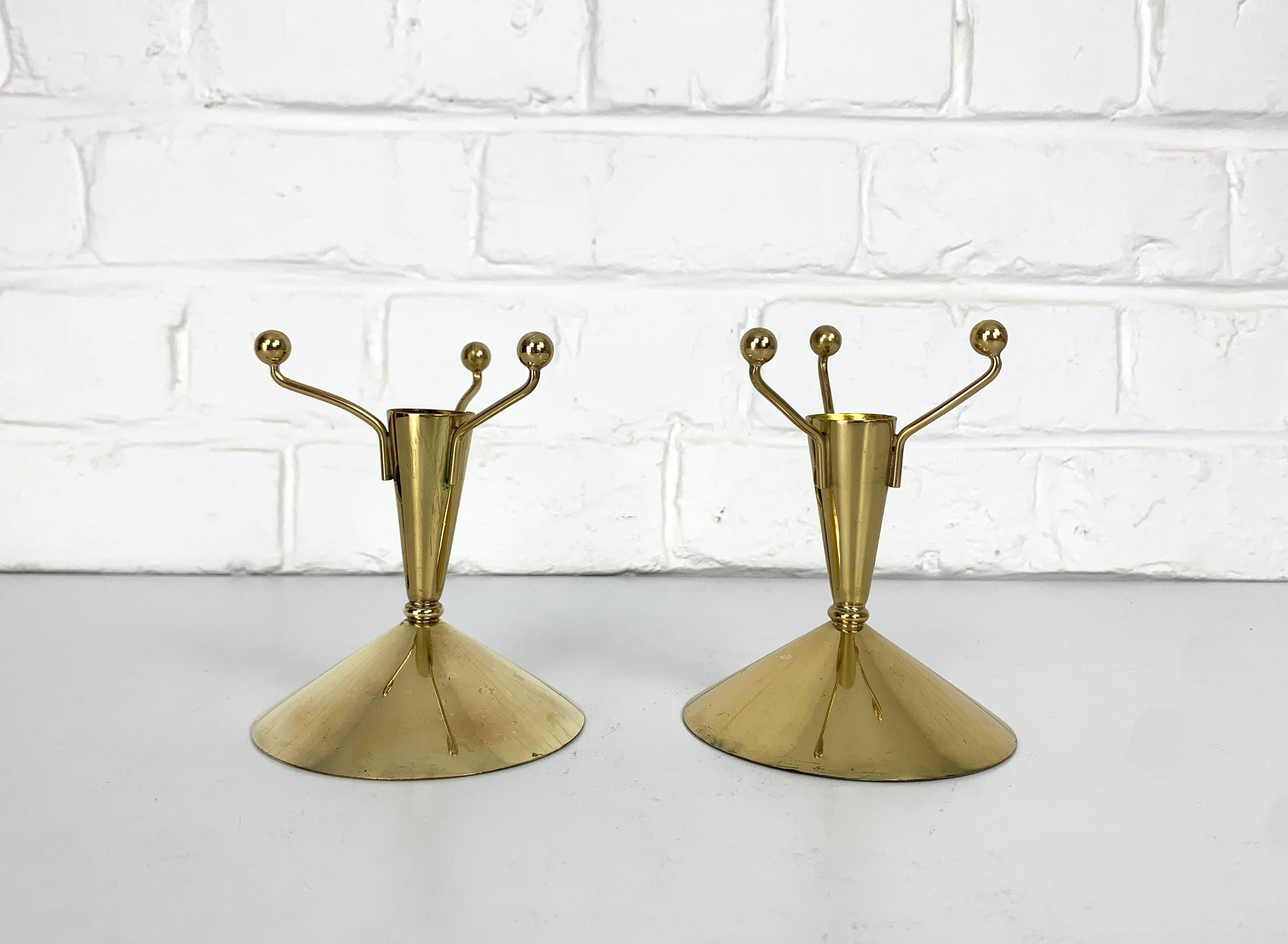 Pair of Swedish Modernist candle-sticks, designed by Gunnar Ander. Produced by Ystad-Metall, located in the town of Ystad in Sweden. 

Entirely made of brass, this playful design is based on a cone with 3 spheres connected by brass rods. It reminds