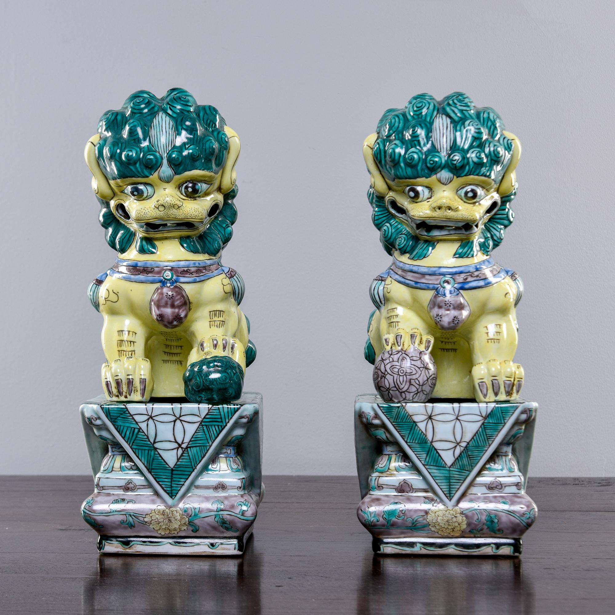 Acquired at a US estate sale, these porcelain Chinese foo dogs date from the 1960s. Dogs are glazed in green and yellow and sit on separate bases. Measurements shown are of dogs on bases as shown in photos. Great color, detail and condition. No