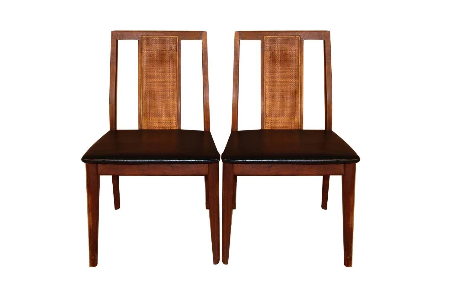 A beautiful pair of Mid-Century Modern chairs in the style of Edward Wormley, manufactured by Hibriten Chair Company of Lenoir NC. This pair features solid walnut frames with black faux leather seats. A Classic minimalistic design with a sleek