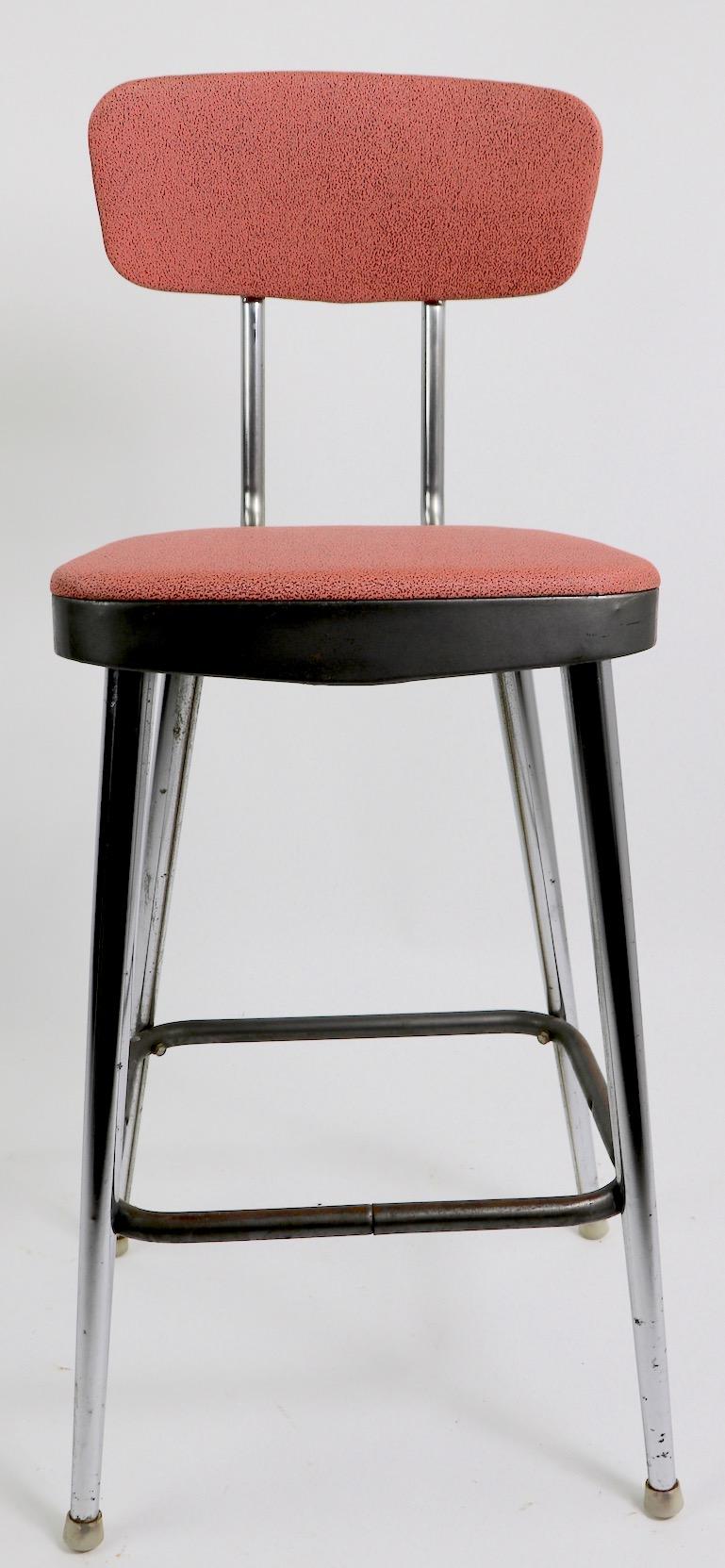 Classic American MCM chrome and rose pink vinyl counter height stools, attributed to Cosco Mfg. Each backrest pad tilts to support your back, and each is adjustable in height as well, to customize to your position. Both stools are in very good,