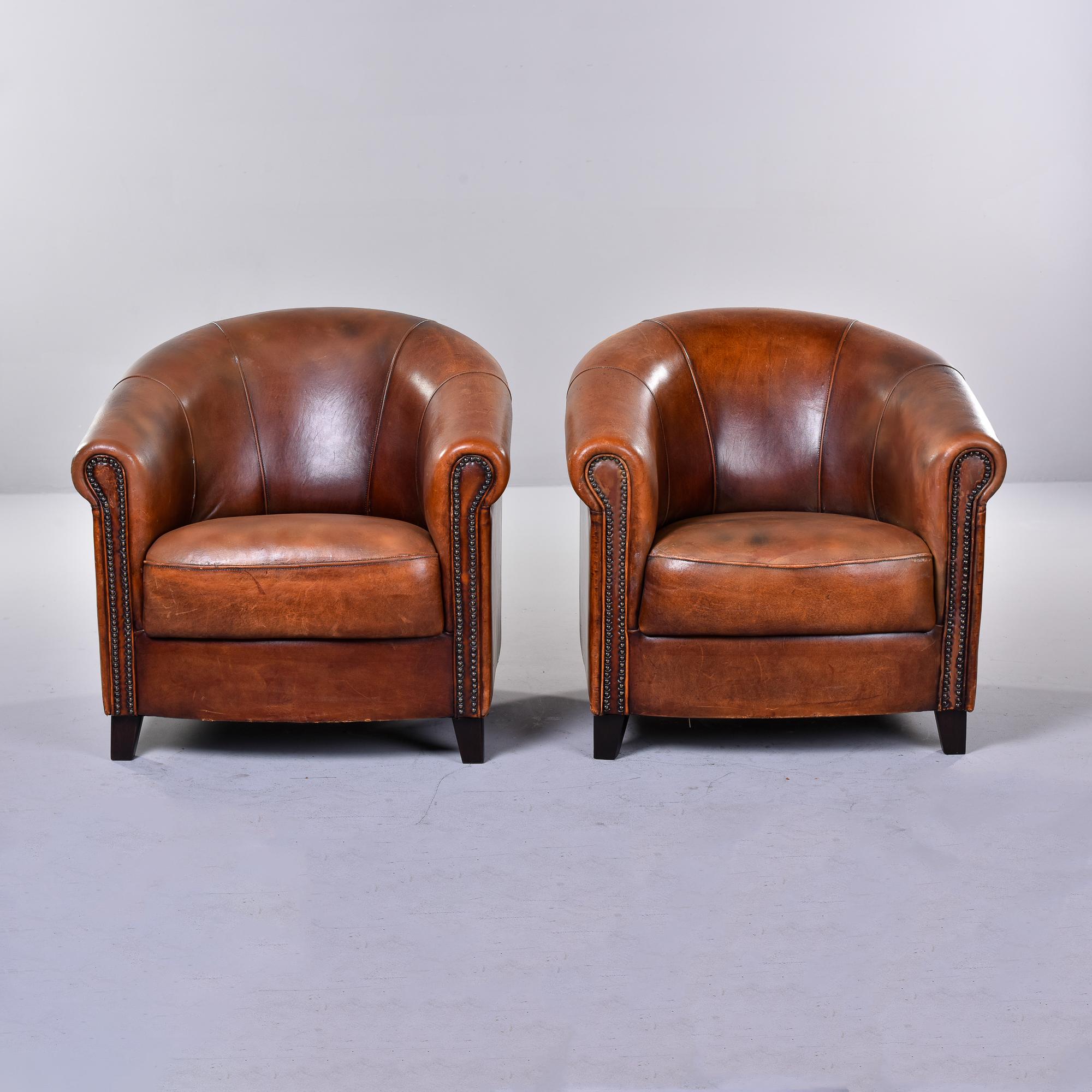 Circa 1980 pair of leather club chairs were made in Netherlands by Joris De Groot. This limited production pair of chairs features thick sheepskin leather that was hand-dyed cigar brown with great patina. Barrel shaped backs, rolled arms with dark