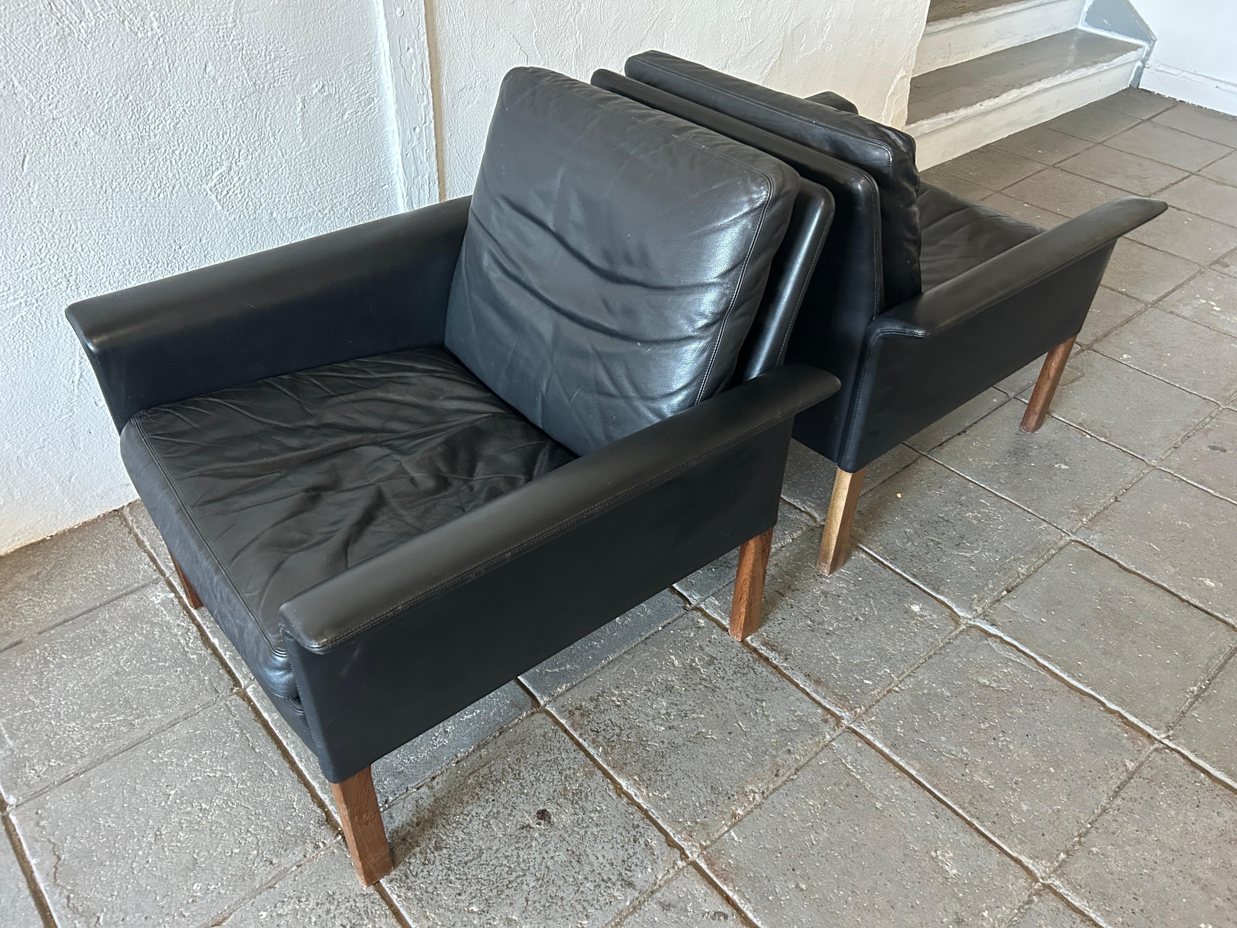 Pair of Mid-Century Modern black leather and rosewood model 500 lounge chairs by Hans Olsen for CS Møbler Glostrup made in Denmark. Constructed of solid Brazilian rosewood and original broken in black genuine leather this modern design is
