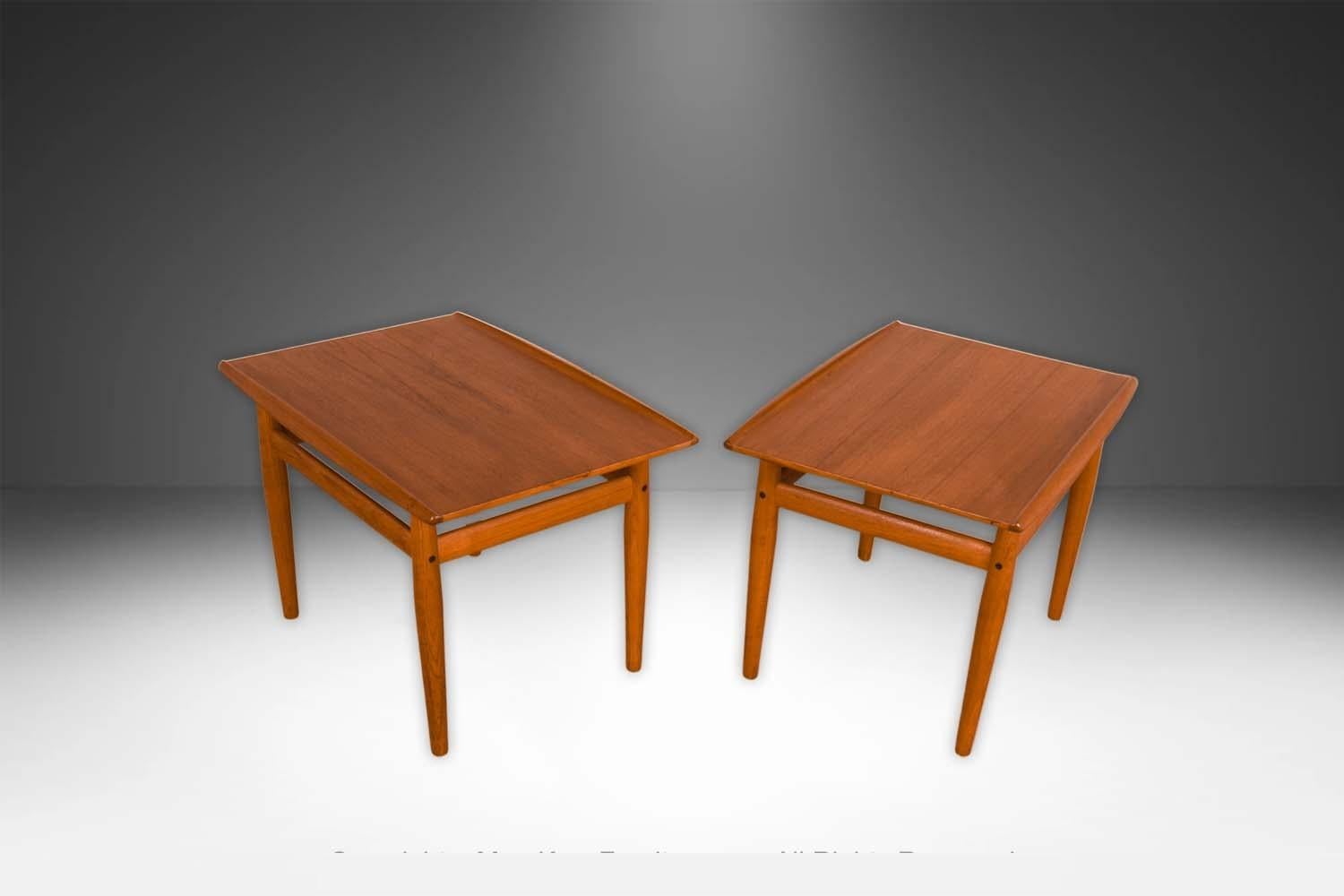 Una bellissima coppia di tavolini danesi in teak della metà del secolo scorso, realizzati da Grete Jalk per Glostrup Mobelfabrik, intorno al 1960. Costruito in teak massiccio. Ciascuna è caratterizzata da un bordo curvo e scolpito che corre lungo i