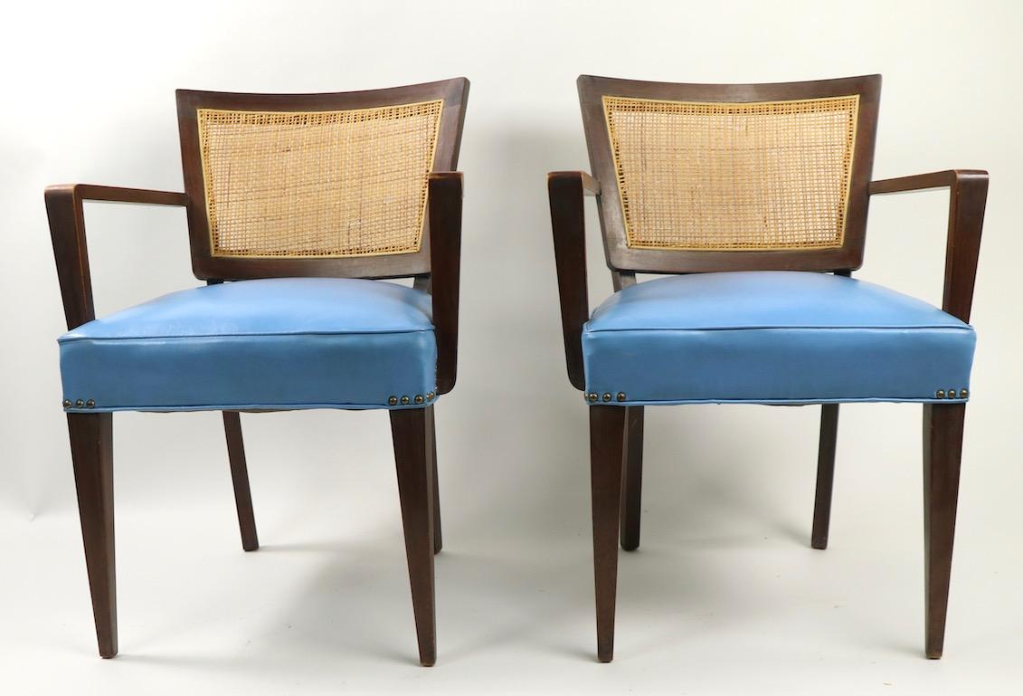 Well designed and crafted pair of Mid-Century Modern armchairs attributed to Harvey Probber. Both have curved and caned back rests, tied spring upholstered vinyl upholstered seats and solid wood, probably walnut, frames. Both show cosmetic wear, and