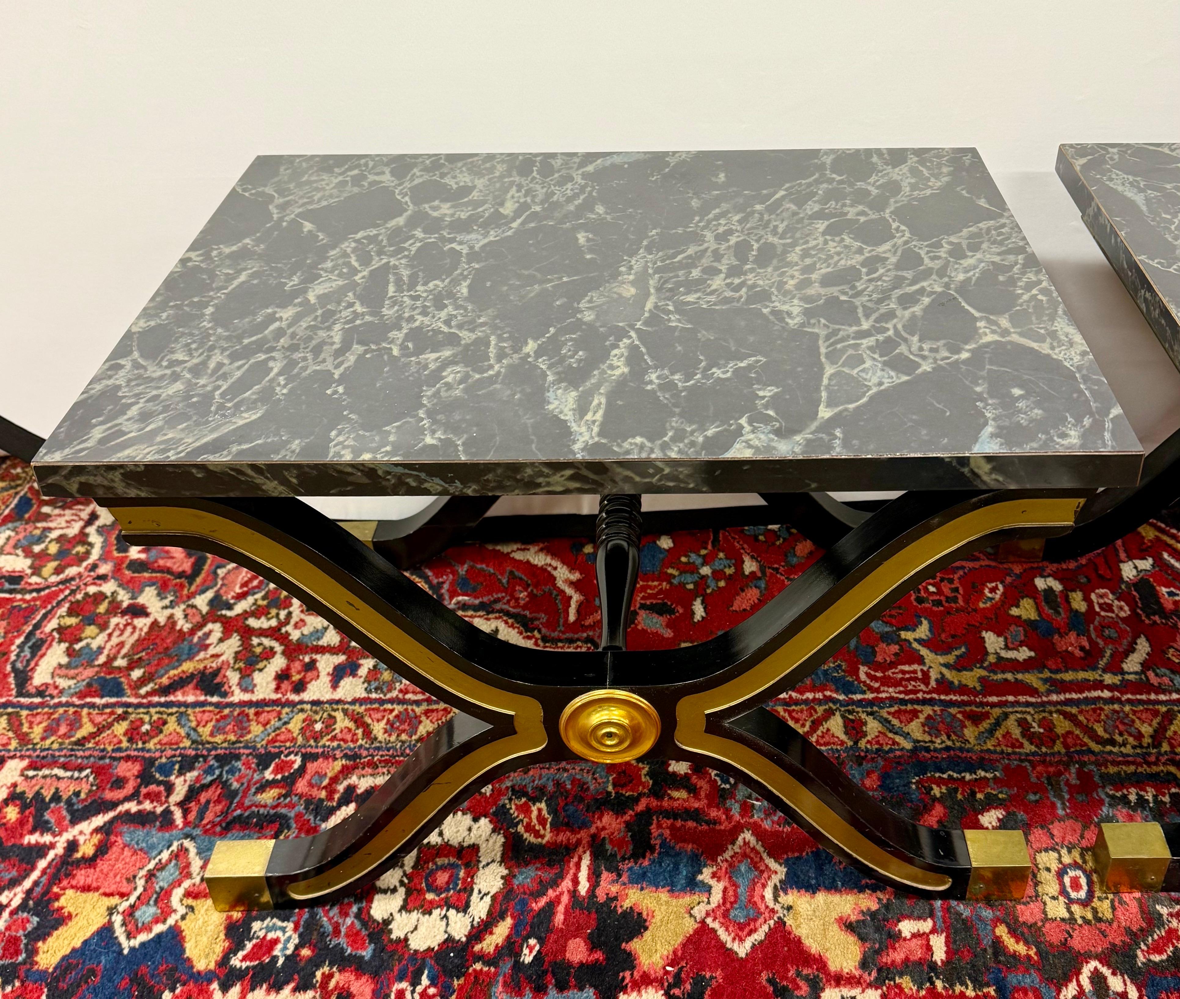 Rare paire de Dorothy Draper Espana avec des bases noires et dorées peintes à la main. La base supporte un plateau en faux marbre.  Ils sont tout simplement exquis.  Les bases noires élégantes avec des formes en X entrecroisées, accentuées par des