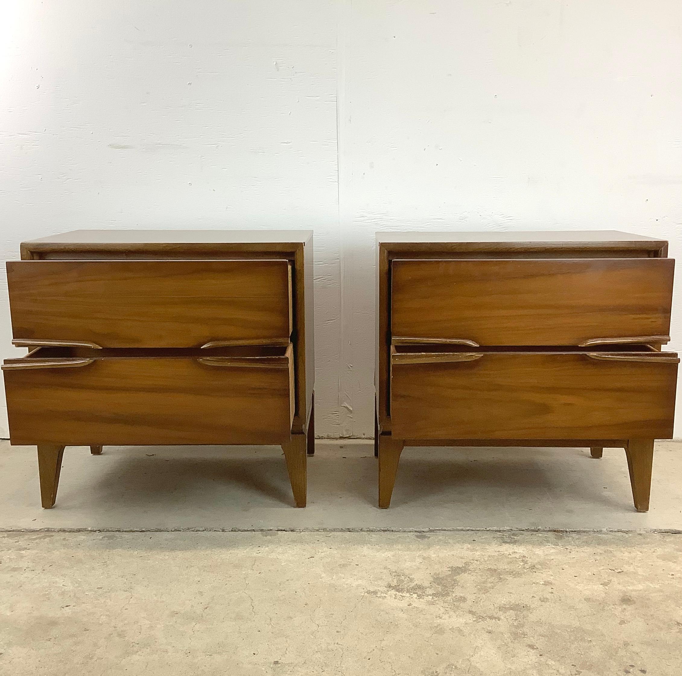 This matched pair of Mid-Century Modern Walnut Two Drawer Nightstands are designed to seamlessly combine both style and functionality. The exquisite pair are crafted with quality mid 20th century quality and plenty of bedside storage-  enhance your