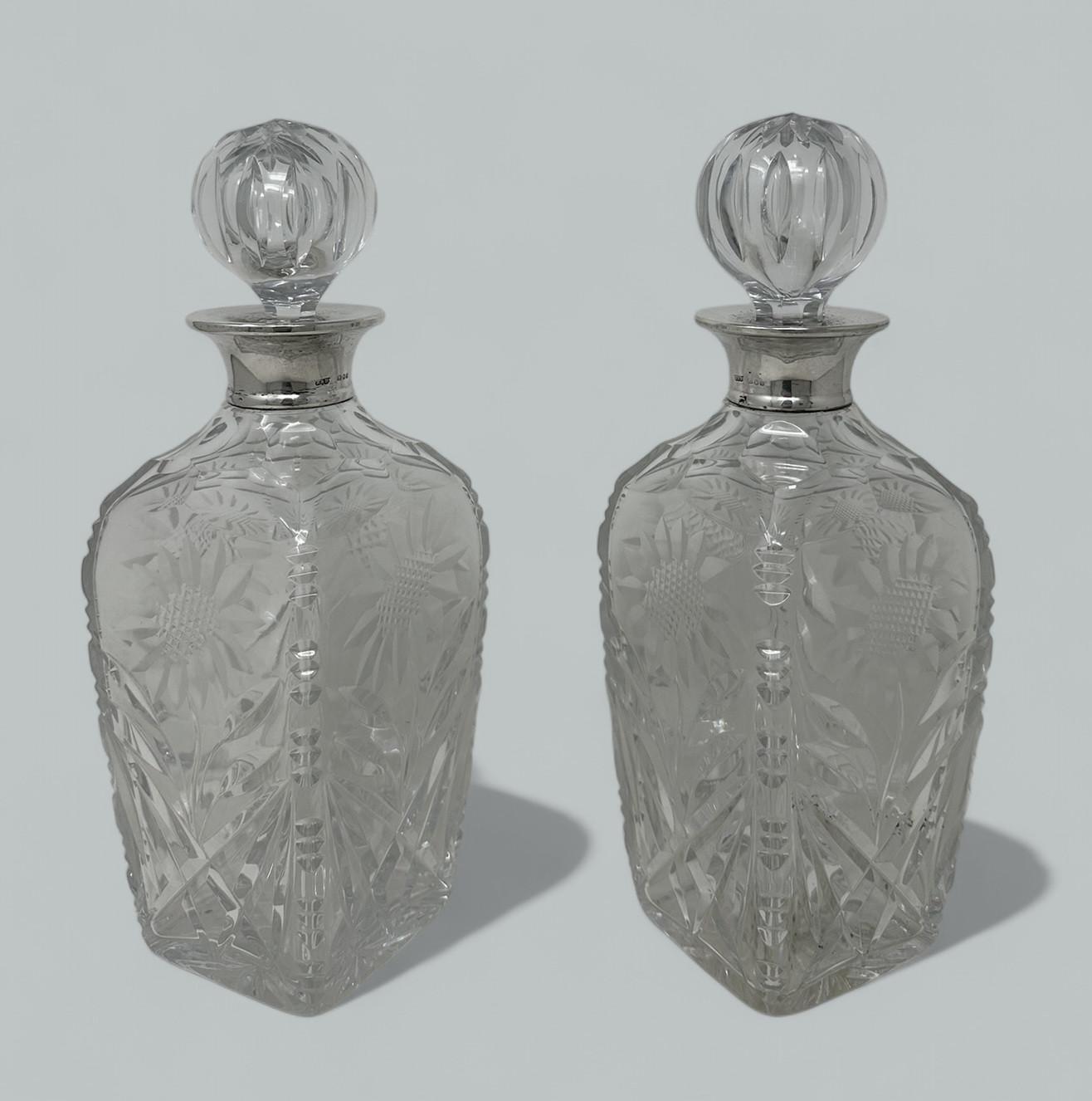 Superbe paire identique de carafes à vin ou à spiritueux en cristal monté en argent sterling, fabriquées par les orfèvres renommés Roberts et Dore de Hatton Garden, Londres, Angleterre. 
Le contour carré du corps est richement découpé à la main avec