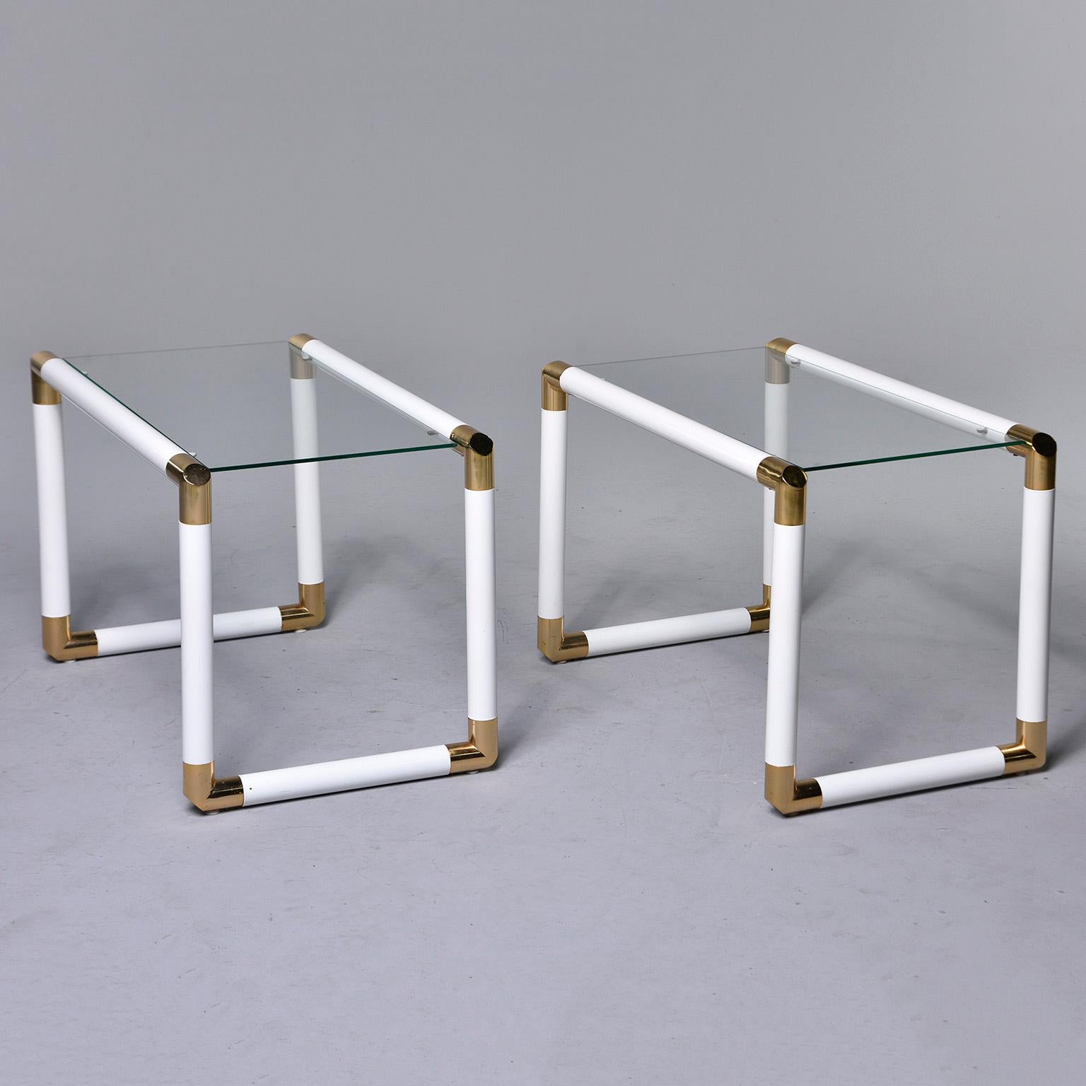 Pair of occasional tables feature white enameled metal tubular frames with polished brass joiners/hardware and clear glass tops, circa 1970s. Unknown maker. Sold and priced as a pair.