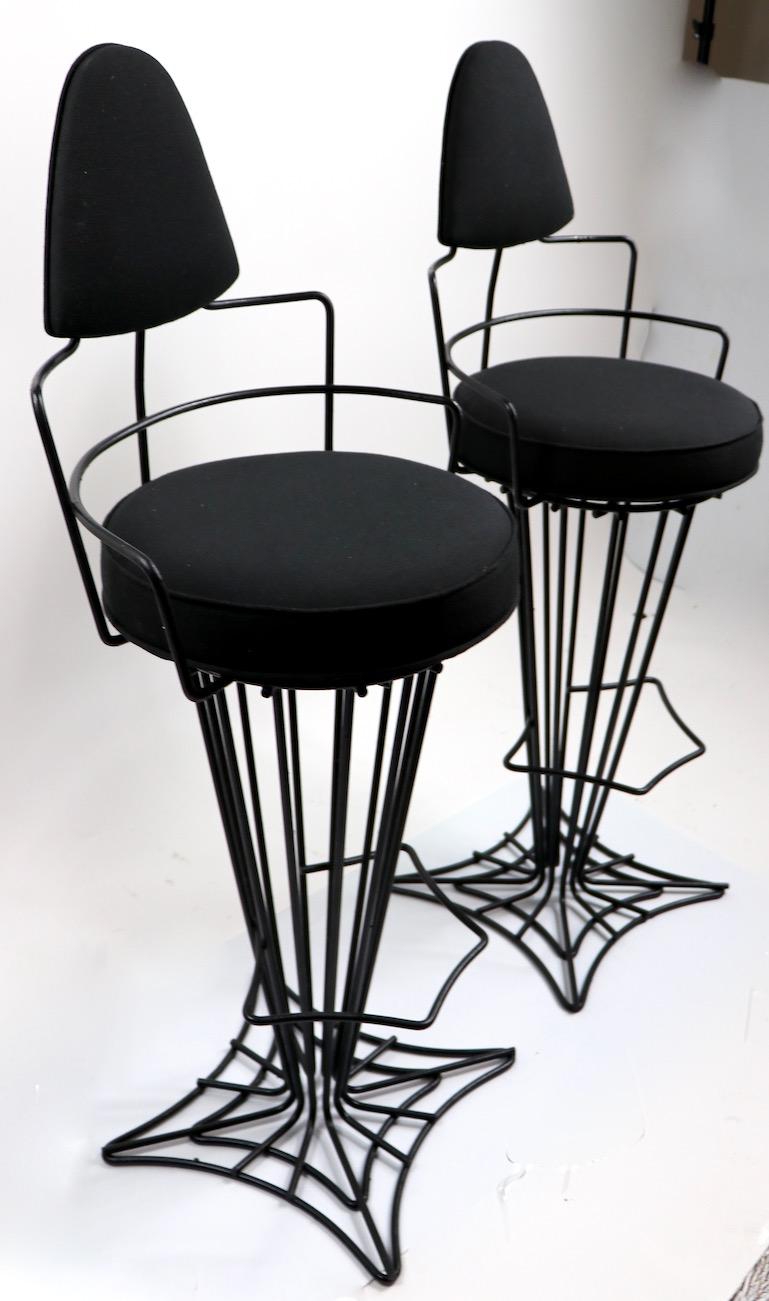 Dramatic and stylish midcentury counter, bar stools with wrought iron frames with upholstered seats and backs. The metal frames have been newly repainted in semi gloss black finish, the seats and backs are newly reupholstered. Design in the style of
