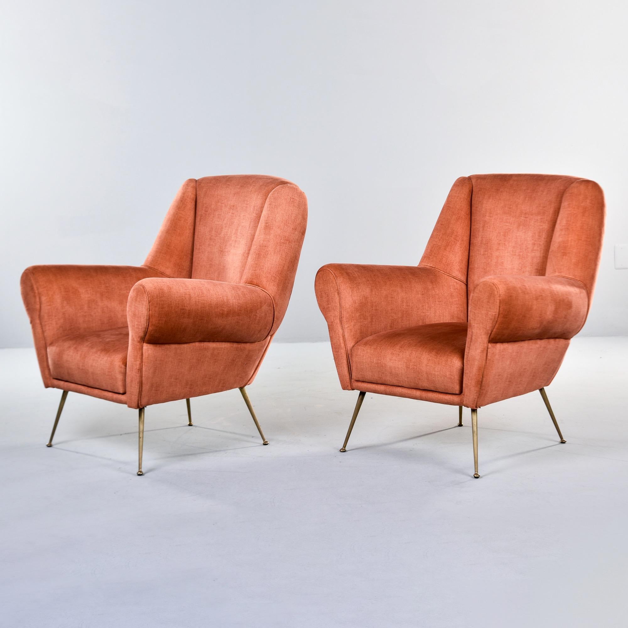 Found in Italy, this pair of upholstered lounge chairs dates from the 1950s. These chairs feature new upholstery in a dark apricot chenille velvet, high backrests, rolled arms and slender brass legs and feet. Unknown Italian maker. Sold and priced
