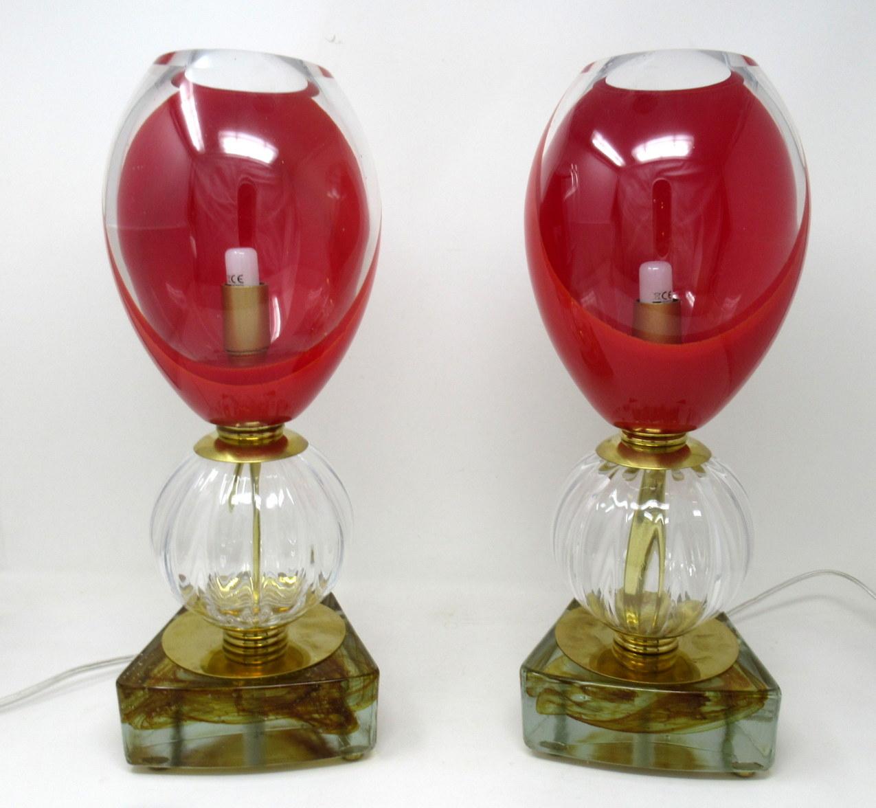 An exceptional and stylish pair of midcentury Italian Murano glass electric table lamps, circa 1950s-1960s

The bulbous body in clear ribbed glass, below a very heavy gauge egg-form glass shade, part clear and part rich red, supported by a shaped