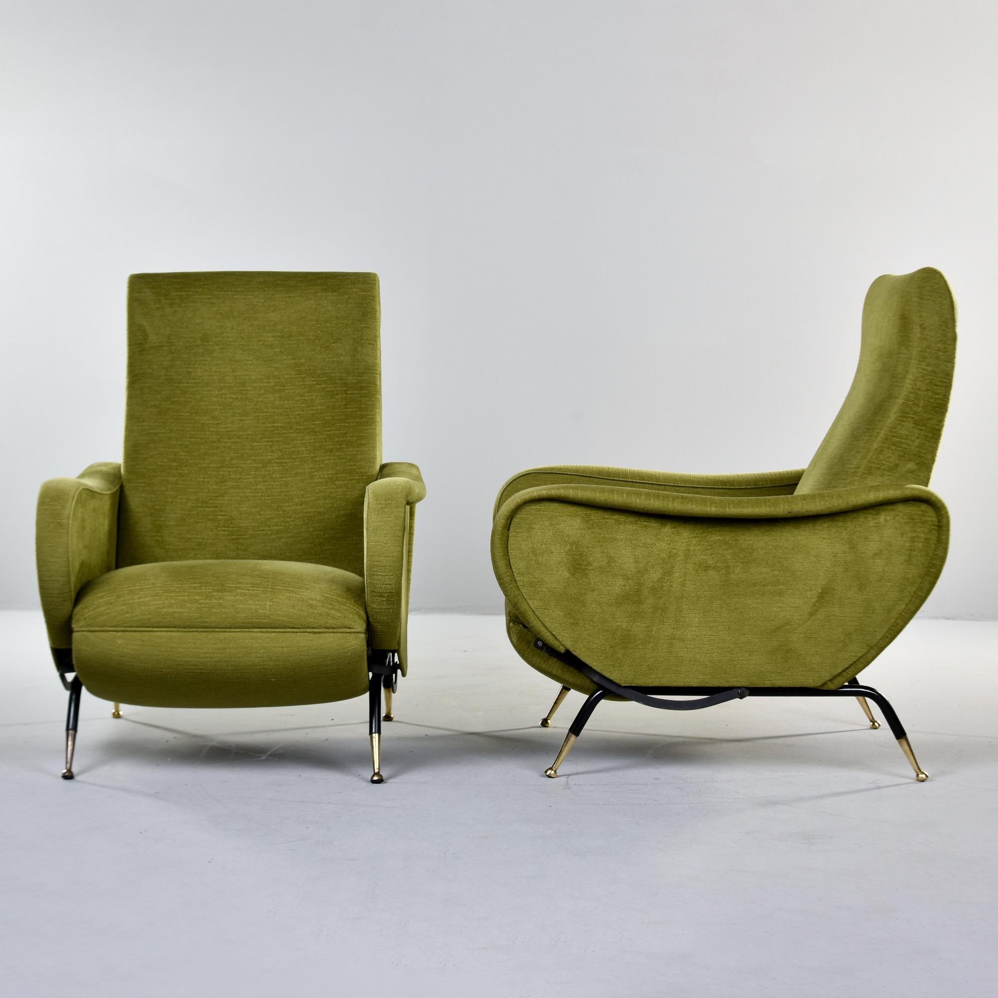 Found in Italy, this pair of reclining lounge chairs dates from the 1950s. Newly upholstered by the Italian dealer we acquired the chairs from in an olive green low-nap chenille. Black metal frame / legs with brass-capped feet. Manual recline