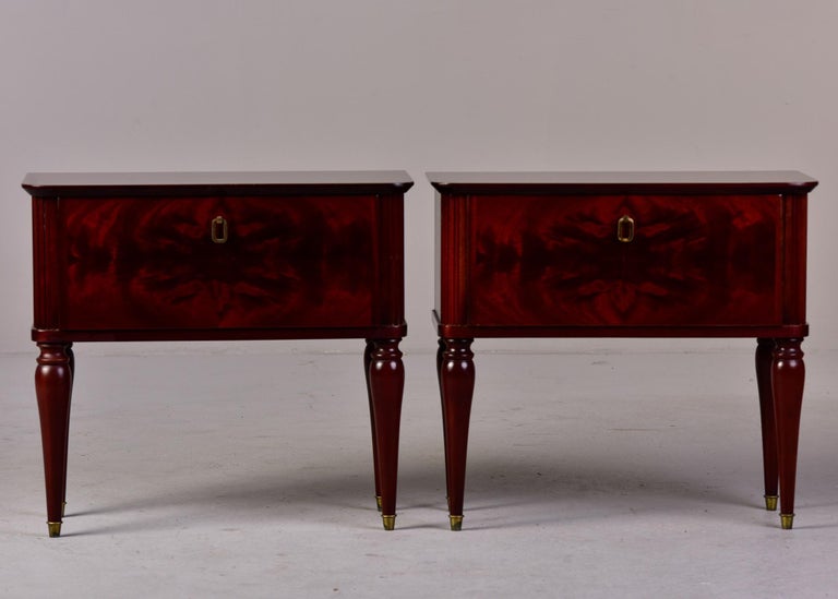 Circa 1960s pair of Italian bedside chests in a dark tiger wood with pull down compartment drawer fronts, tapered legs with brass capped feet. Unknown maker. Sold and priced as a pair.
