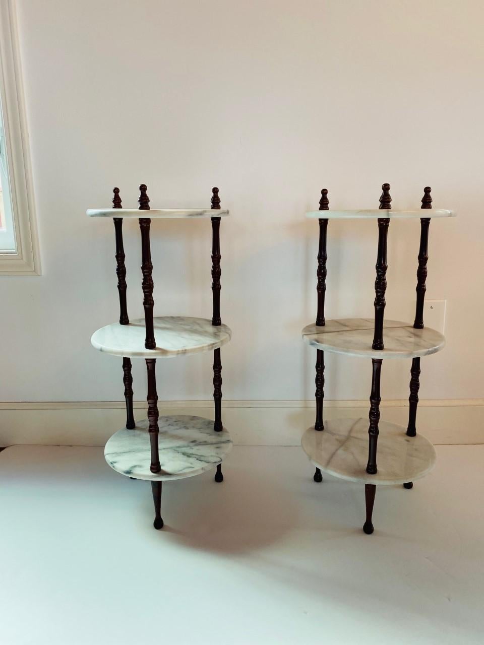 Beautiful pair of 3-tier tables stand. Versatile piece that works with your decor or for accessories or plants. Each presents 3 marble discs entwined within 3 wooden long legs. Classic but unexpected and stylish.