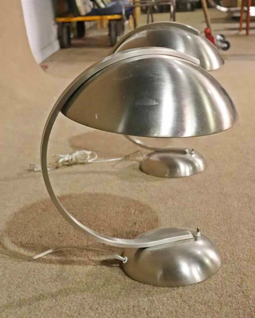 Mid-Century Modern style tables lamps in polished metal. Attractive arching arm with round shade. 
Please confirm location.