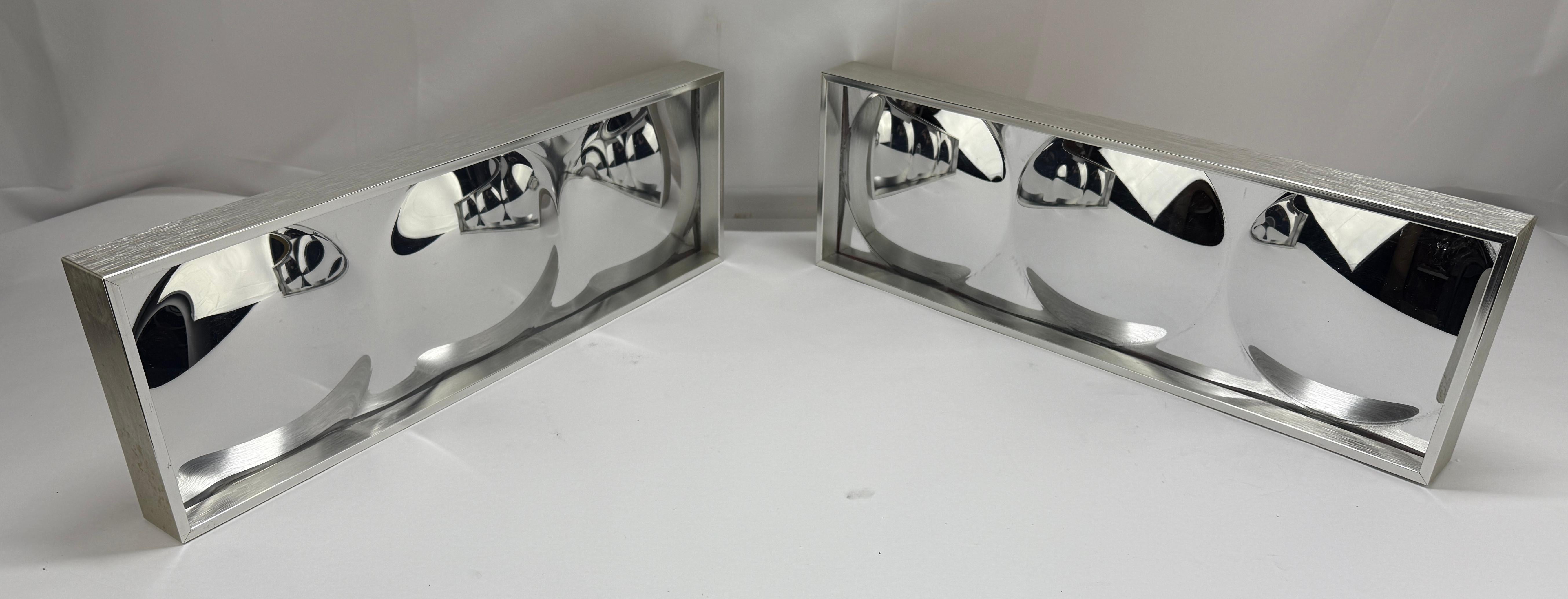 These sleek and sophisticated wall sculptures by Turner Manufacturing Co. feature a mesmerizing optical design with convex circular forms set within polished aluminum frames. Crafted from Plexiglas acrylic, these pieces embody the minimalist,