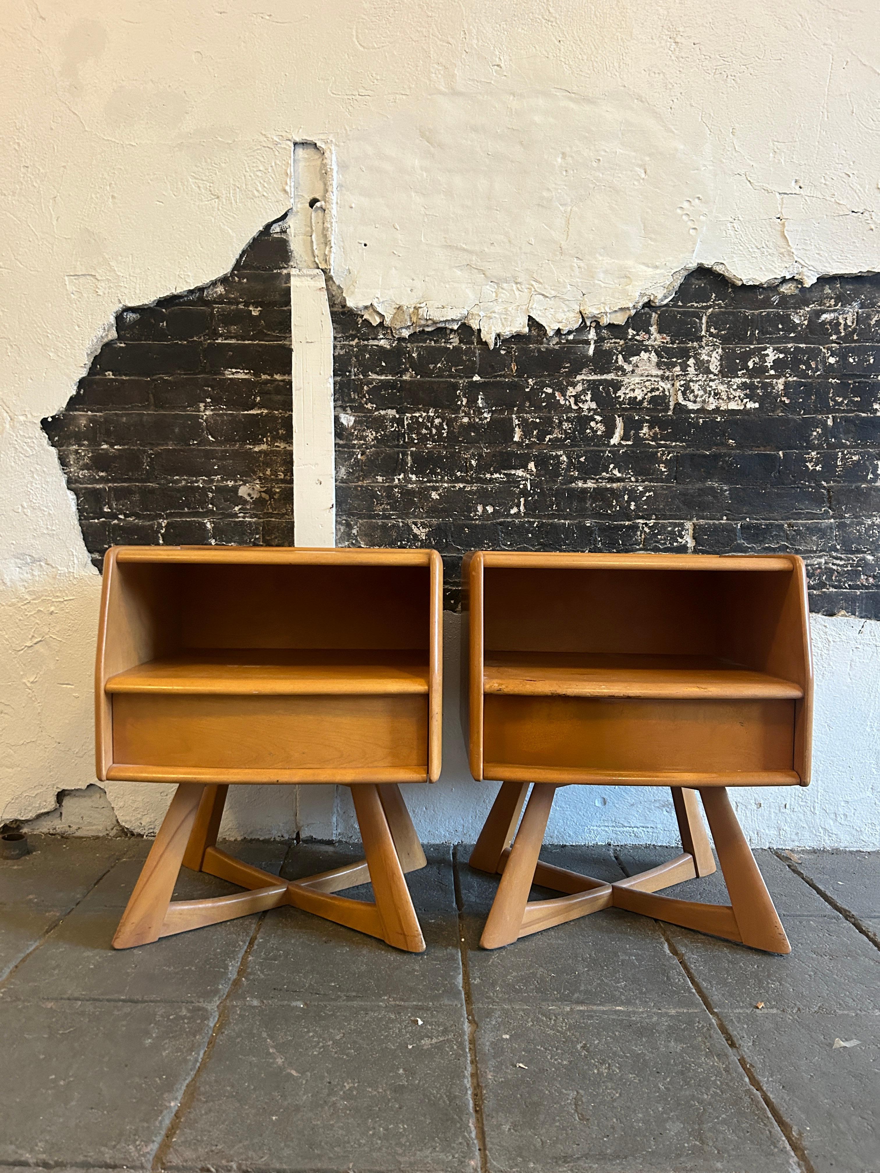 Timeless pair of Heywood Wakefield Mid-Century Modern single drawer nightstands. All solid maple construction with sculpted X base and curved front. Good vintage condition original blonde finish. Circa 1950 - Located in Brooklyn NYC.

Measures 24