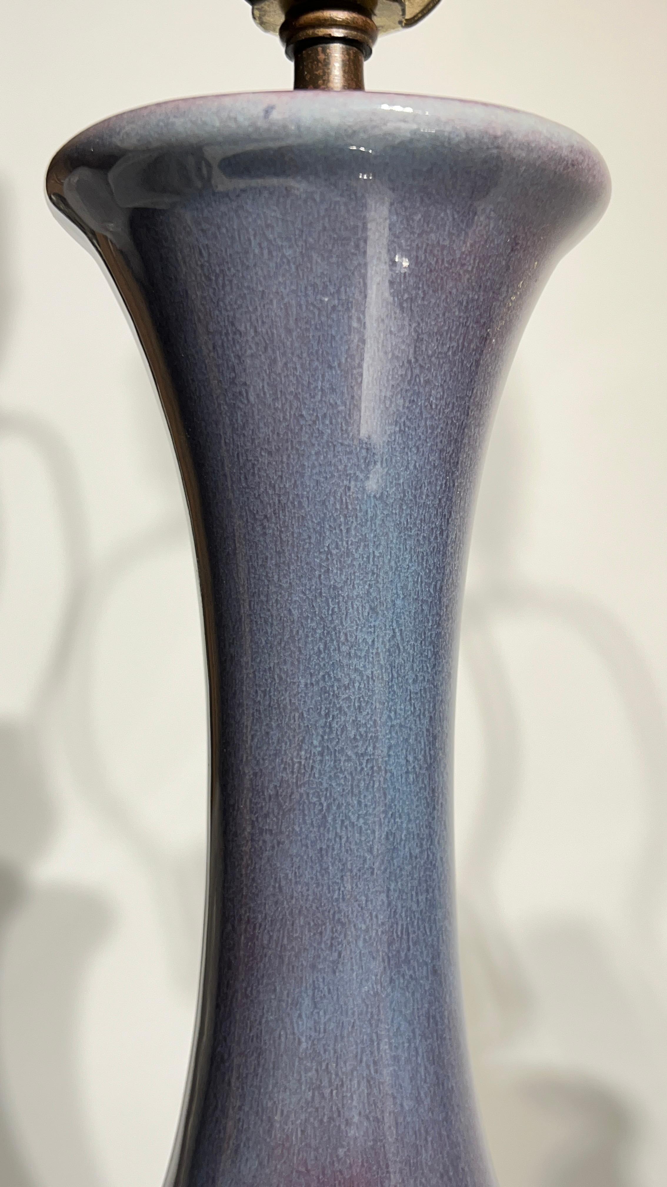 Beautiful pair of mid-century modern period table lamps, circa 1960s, attributed to Royal Haeger, with violet/blue/turquoise flambe glaze and original corn husk form finials.  27 1/2 inches tall and in excellent condition.