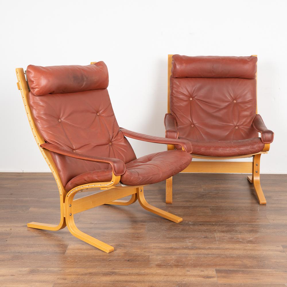 Pair of Mid-Century Modern brown leather lounge chairs.
This pair show cases a traditional molded beechwood frame, complimented with button-stitched rust colored vintage leather including arm rests.
Leather (and frames) shows typical age-related