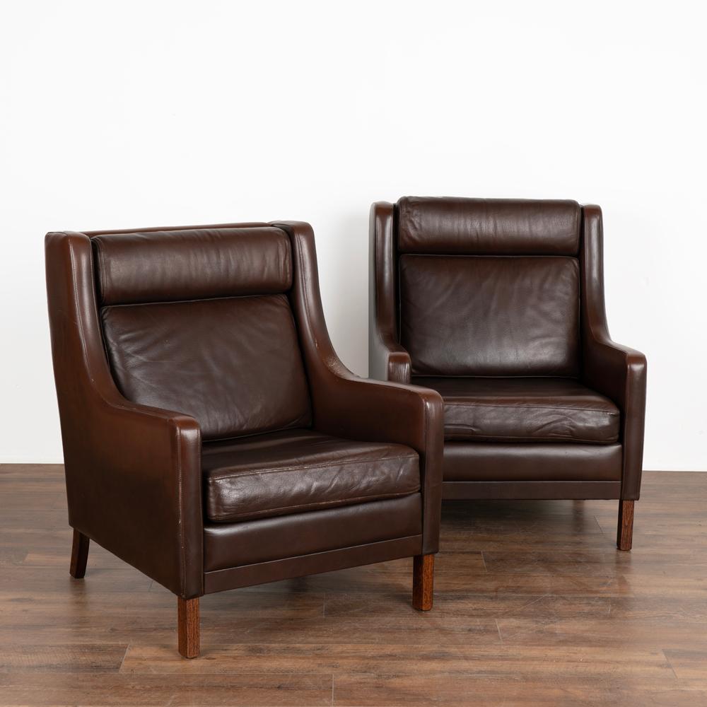 Pair, Mid-Century Modern wingback arm chairs by Mogens Hansen of Denmark.
Vintage brown leather with loose seat and back cushions and legs in solid beech wood.
Sold in solid, vintage used condition; leather shows scratches, scuffs, wear, creases,