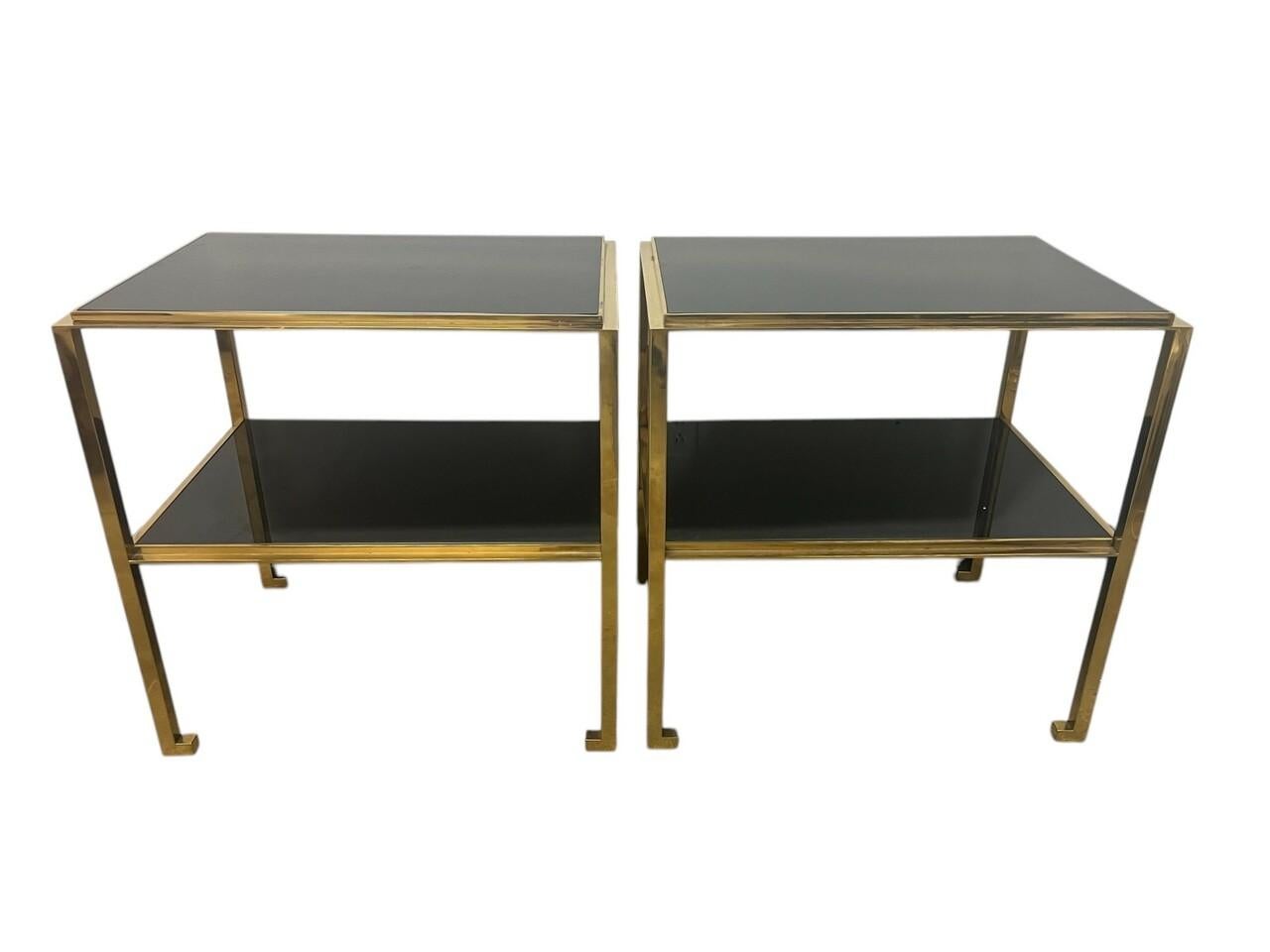 Pair Mid Century Modern Gilt Two -Tiered End Tables with Black Glass. Well made, some tarnishing on the finish in a few spots. One piece of glass has a small chip on the corner, does not jump out and can be placed on lower level. Some scratches as