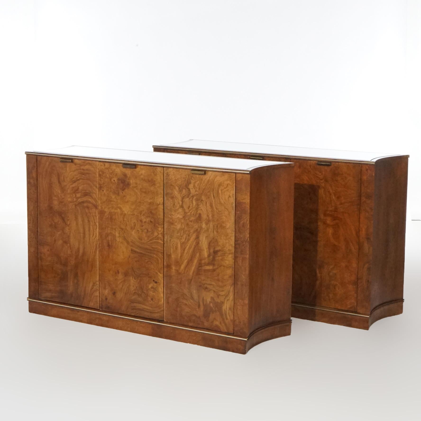 A matching pair of Mid-Century Modern credenzas by Martinsville of America offer walnut construction with concave sides; inset mirror top over case with three drawers having burl facing and opening to interior with shelves and drawers; maker label