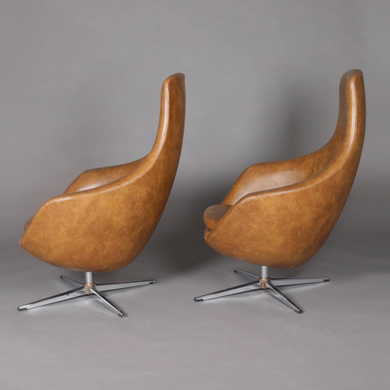 Pair of Mid-Century Modern Overman school womb or egg chairs feature button back faux leather upholstery and are raised on swivel chrome base, circa 1960

Measures: 42
