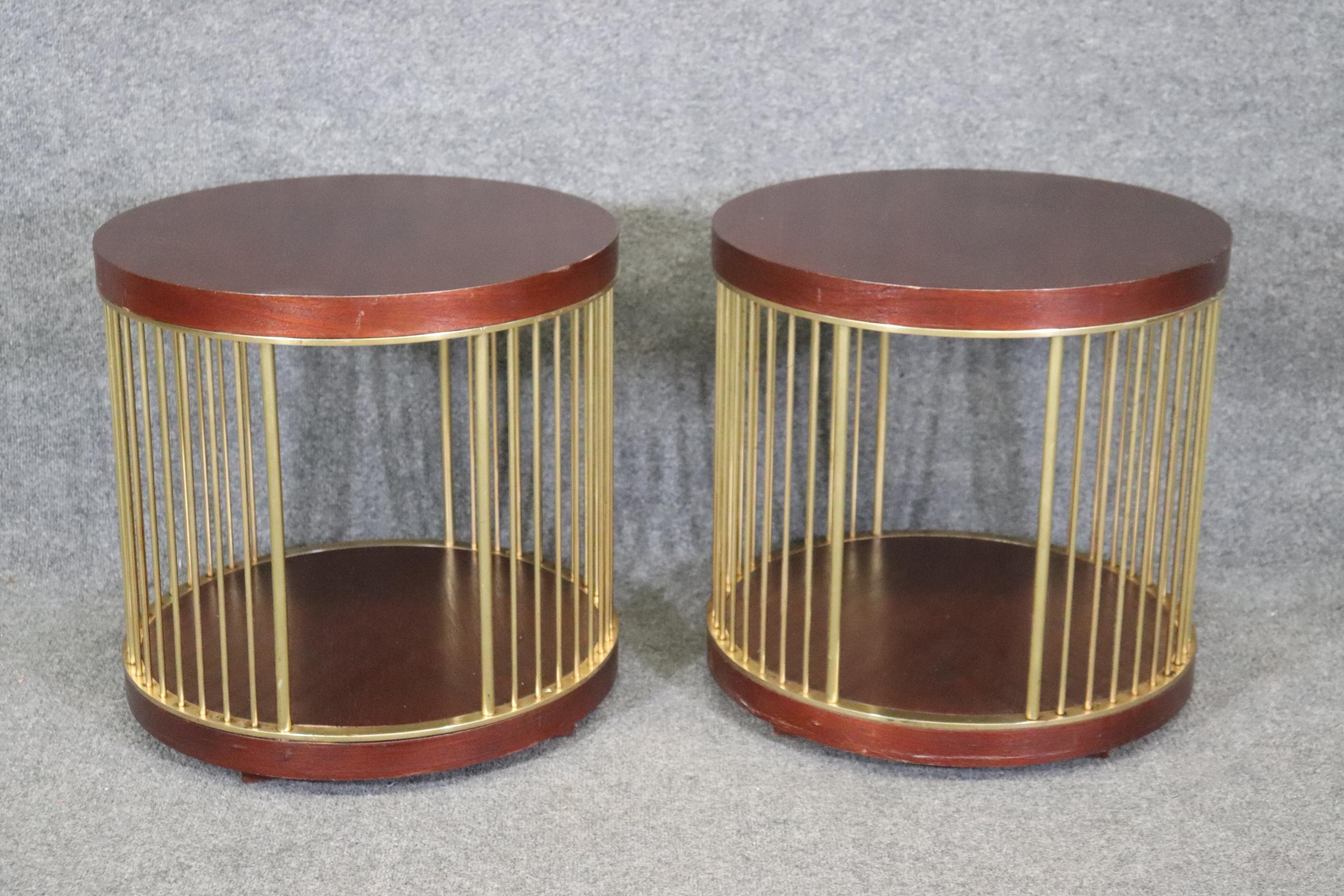 This is a gorgeous pair of Paul McCobb style circular end tables with brass rods and a cage style base with mahogany tops and bases. The tables are in good used condition with minor scuffs and signs of use. The tables are each from the 1970s era and