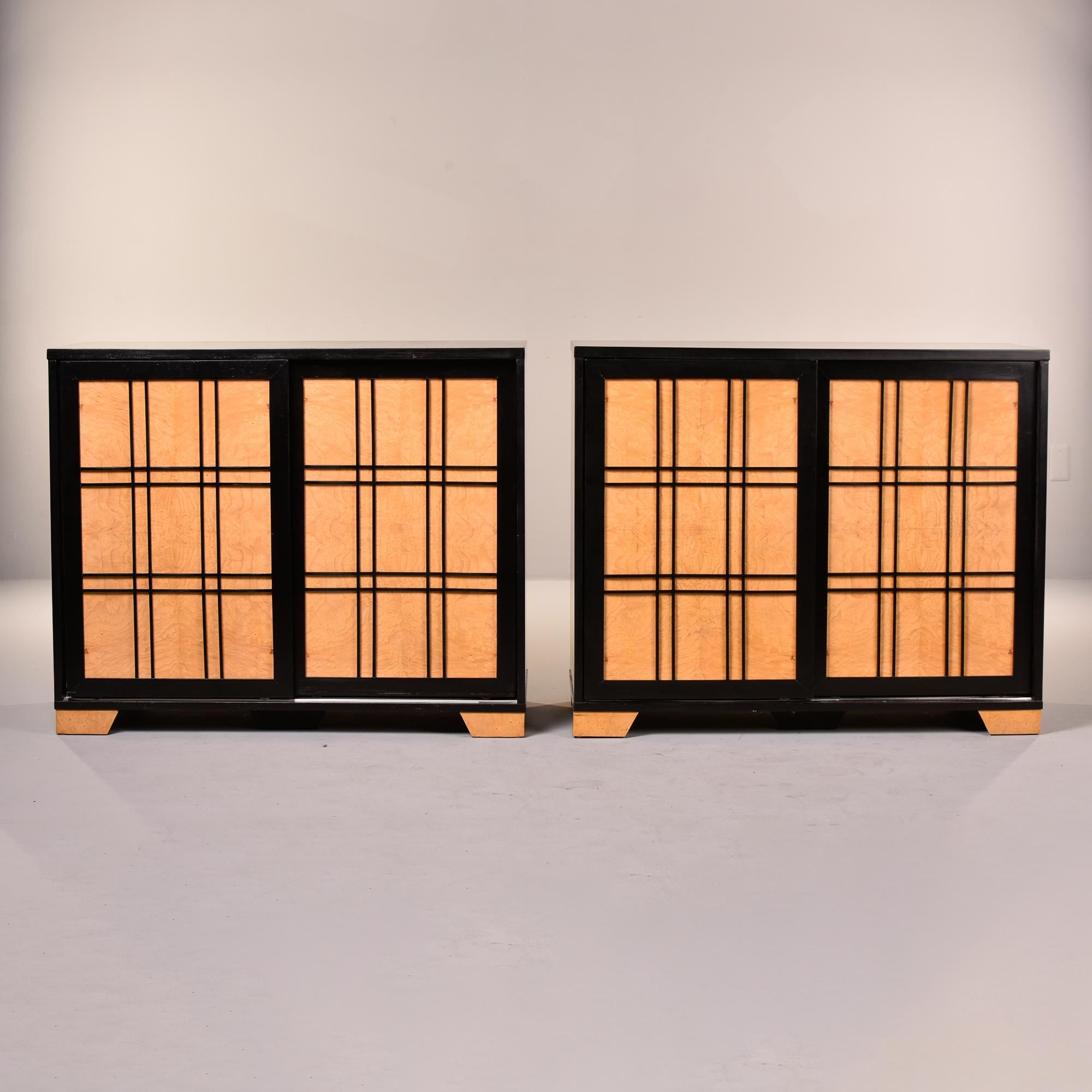 Found in France, this pair of circa 1980s side cabinets each feature ebonised frames and decorative grid work with contrasting maple panel doors. Each cabinet has two sliding panel doors that opens to a single fixed shelf and lower drawer on each