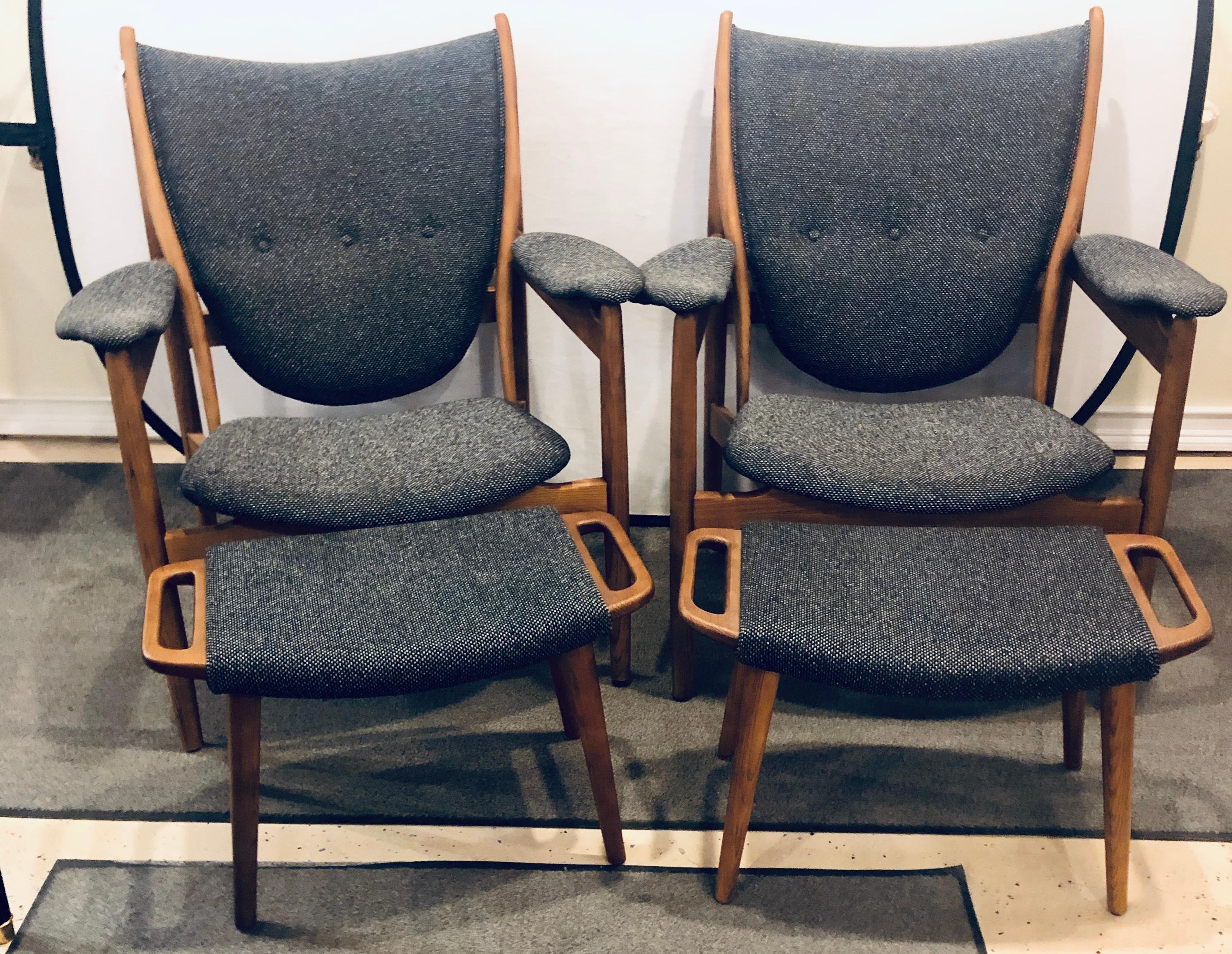 Pair of Mid-Century Modern arm chairs along with ottomans. Each in a fine newly Upholstered fabric having a Graphite Tweed. The pair having wide sturdy seats. 

Measures: Chair: 37 inches H x 33 inches W x 28 inches D
Ottoman: 15 1/2 inches H x
