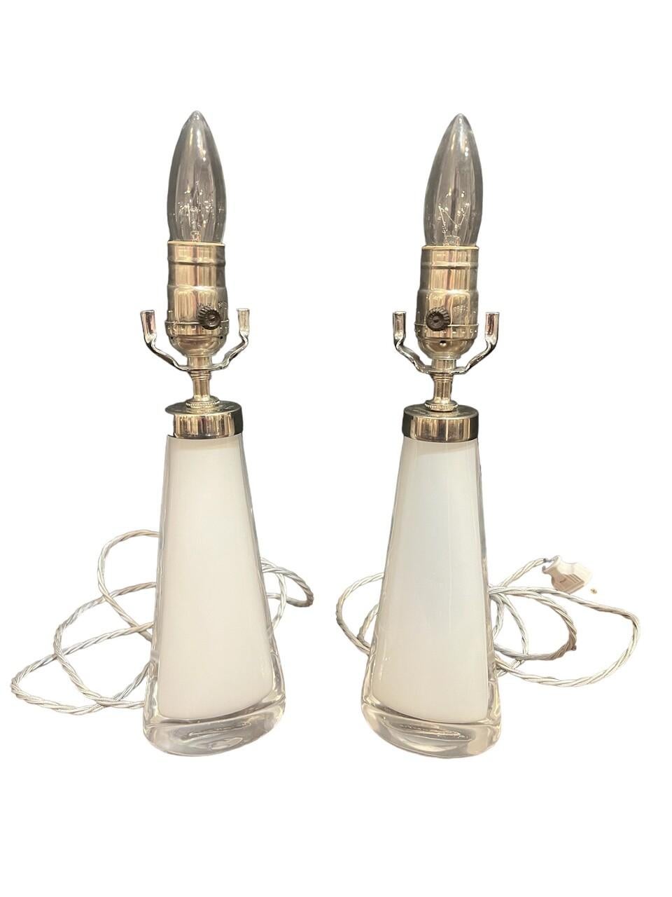 Pair of mid-century modern Swedish Orrefors glass lamps, circa 1960s. These elegant creations feature sleek white glass with gentle curves, embodying the minimalist charm of the era. Designed to enhance any space with their understated