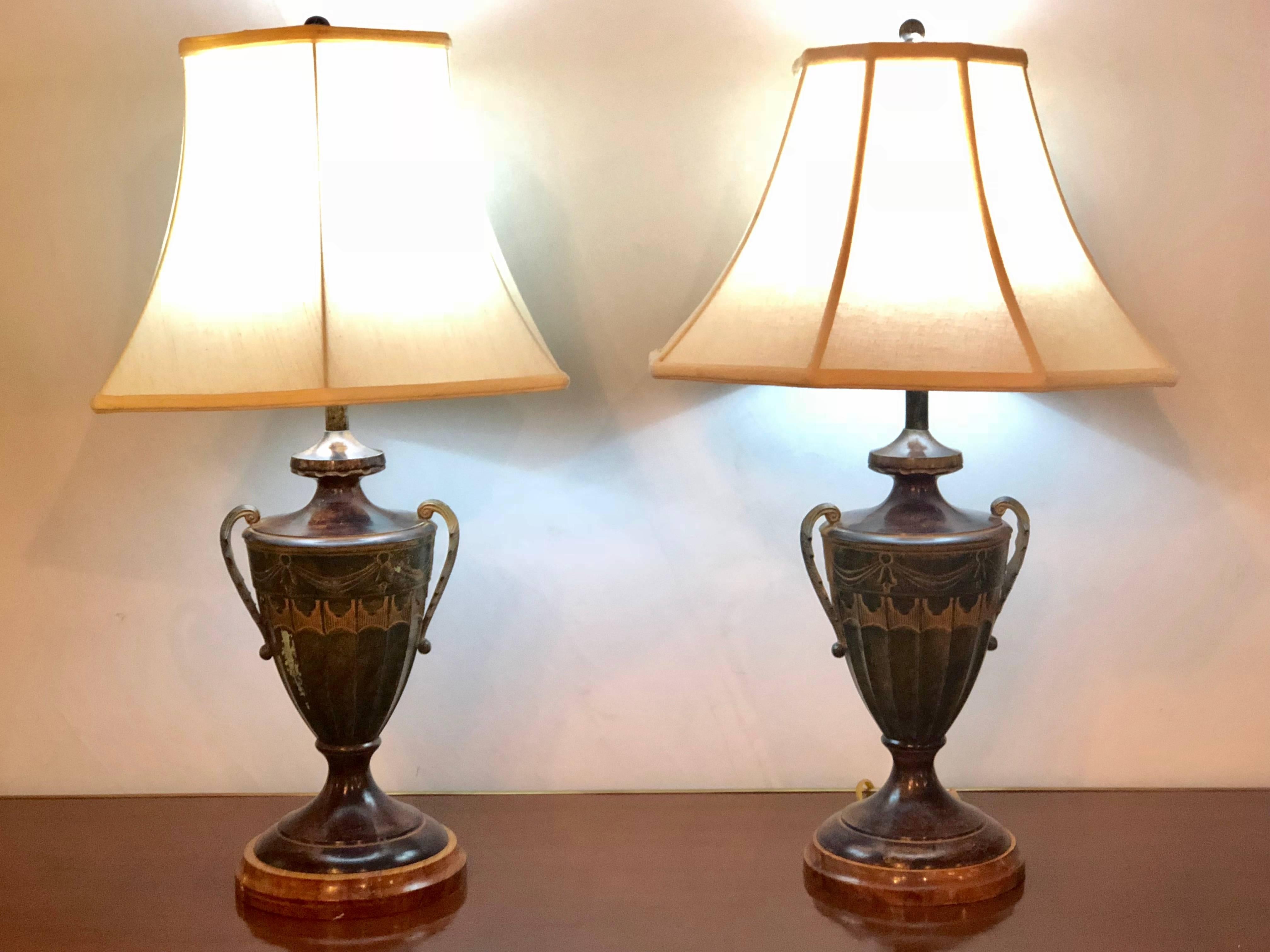 Pair of Mid-Century Modern Style Urn Form Gilt Painted Table Lamps. Both in a green color with tassel and ribbon decorations these twin handled Aladdin lamps are certain to add style and grace to your living area. 