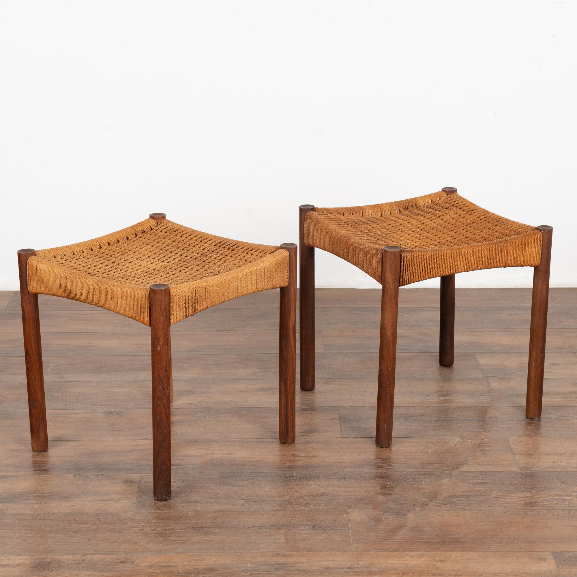 Stylish pair of Mid-Century Modern stools in hand-woven cord or rope with teak wood frame with traditional clean lines. 
This versatile and attractive pair of stools is solid, stable and ready for use. 
In original condition with wear consistent