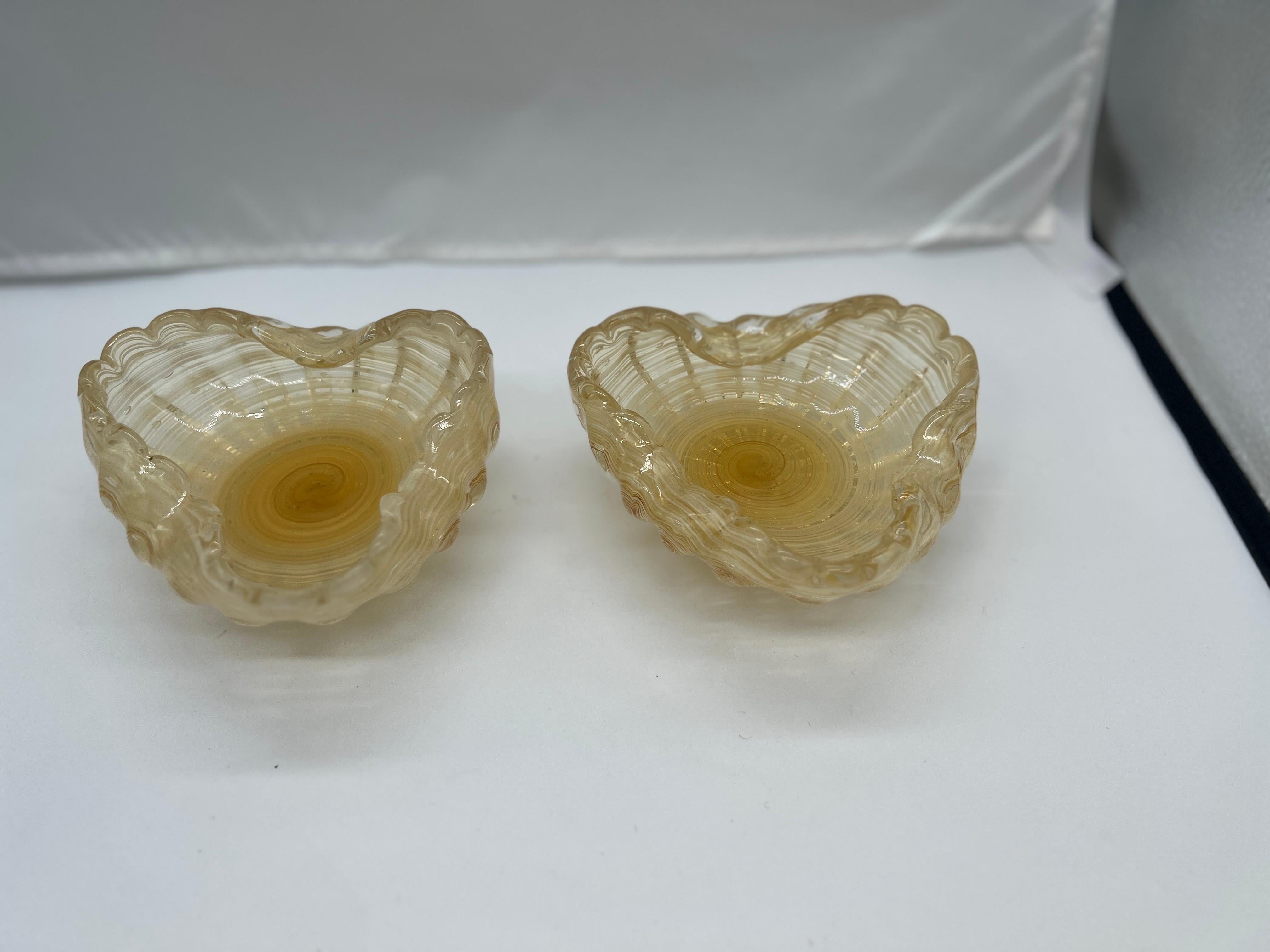 Italian Murano, 20th century.

A pair of beautiful gold speckled Murano Art Glass catch-all dishes or ashtray bowls. Each piece has a 3 flattened lips for resting objects. The base with a swirled foot and cut pontil. Unmarked.