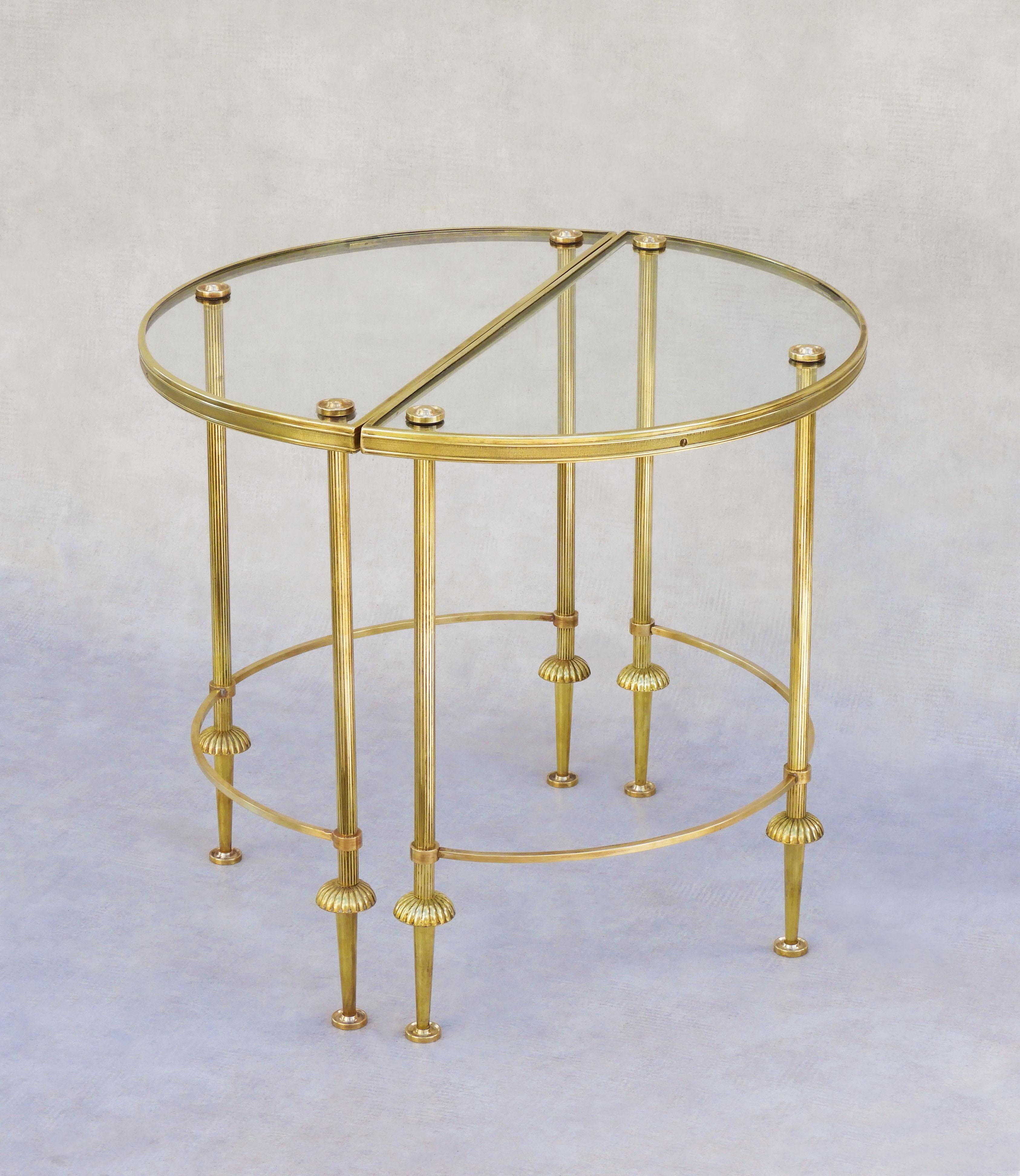A charming pair of mid-century neoclassical brass & glass demi-lune Tables C1950s attributed to Maison Baguès.  Each table stands on three fluted legs with tapered feet, a curved stretcher reflects the shape of the half-moon glass top, which is