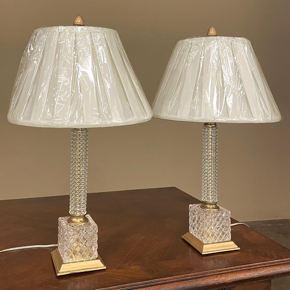 Pair Mid-Century Neoclassical Cut Crystal & Brass Table Lamps feature a design influenced by neoclassical architecture, yet rendered with a modern flair.  The diamond patterns of the design provide an opulent look, with a round cylindrical shaft set