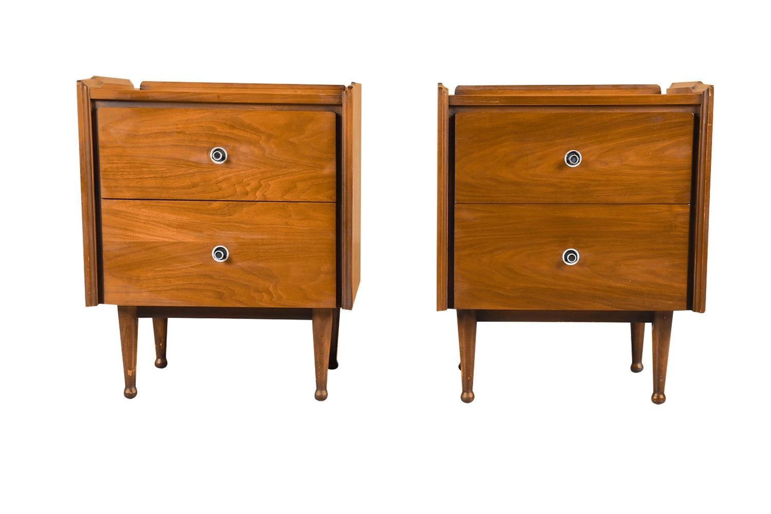 Stunning walnut Mid-Century Modern pair of nightstands for Mainline by Hooker Furniture Company circa 1960’s. A beautiful example of Mid-Century craftsmanship, each features sculpted raised backsplash and side edges above 2 drawers. Manufacturer’s