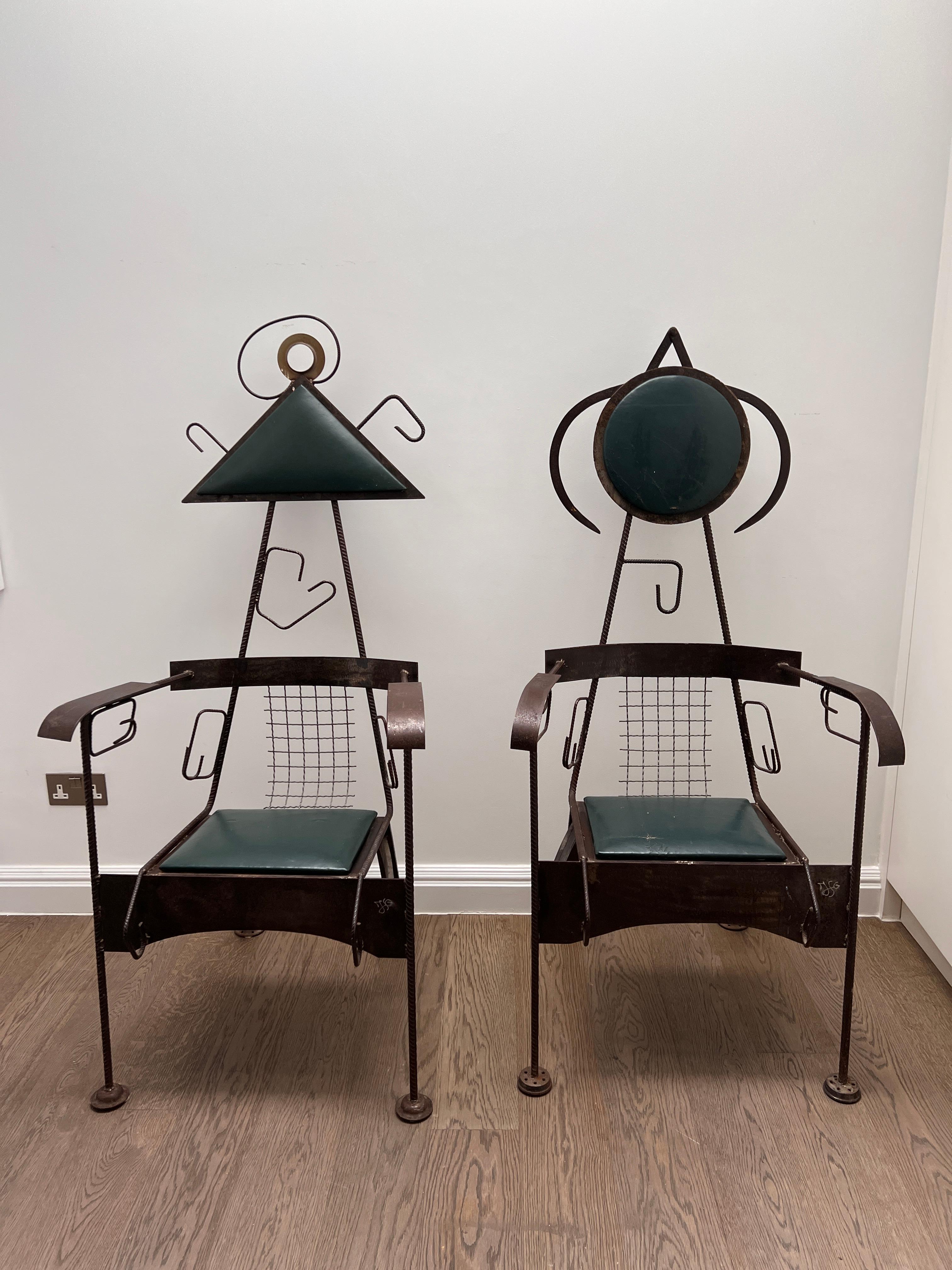This striking pair of sculptural mid-century modern chairs effortlessly blends form and function. Their tall, commanding presence is defined by a crafted metal frame, featuring whimsical, abstract detailing reminiscent of Joan Miró’s playful