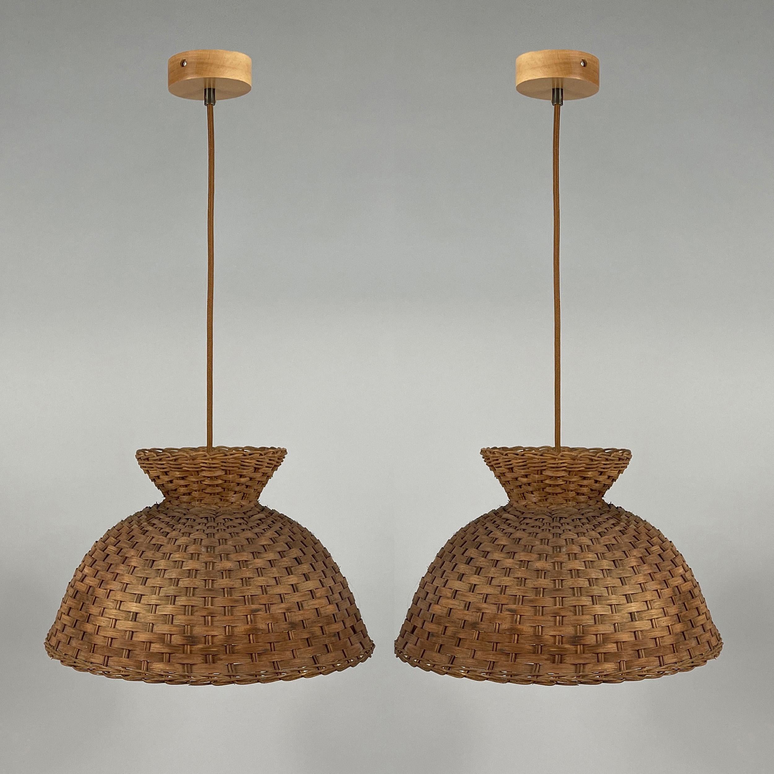 Swedish Mid-Century Design Rattan Pendants, 1960s

The lights feature handwoven rattan shades in a warm, natural tone, shaped into a unique hourglass-like silhouette with a slightly flared top. The intricate wicker pattern allows for a soft