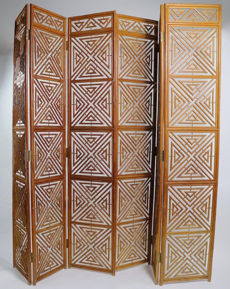 Chic and decorative pair of freestanding folding screens, of reed wicker configured in an architectural geometric pattern. Each screen has three rectangular panels, hinged together enabling the screen to expand or contract to work in your space. We
