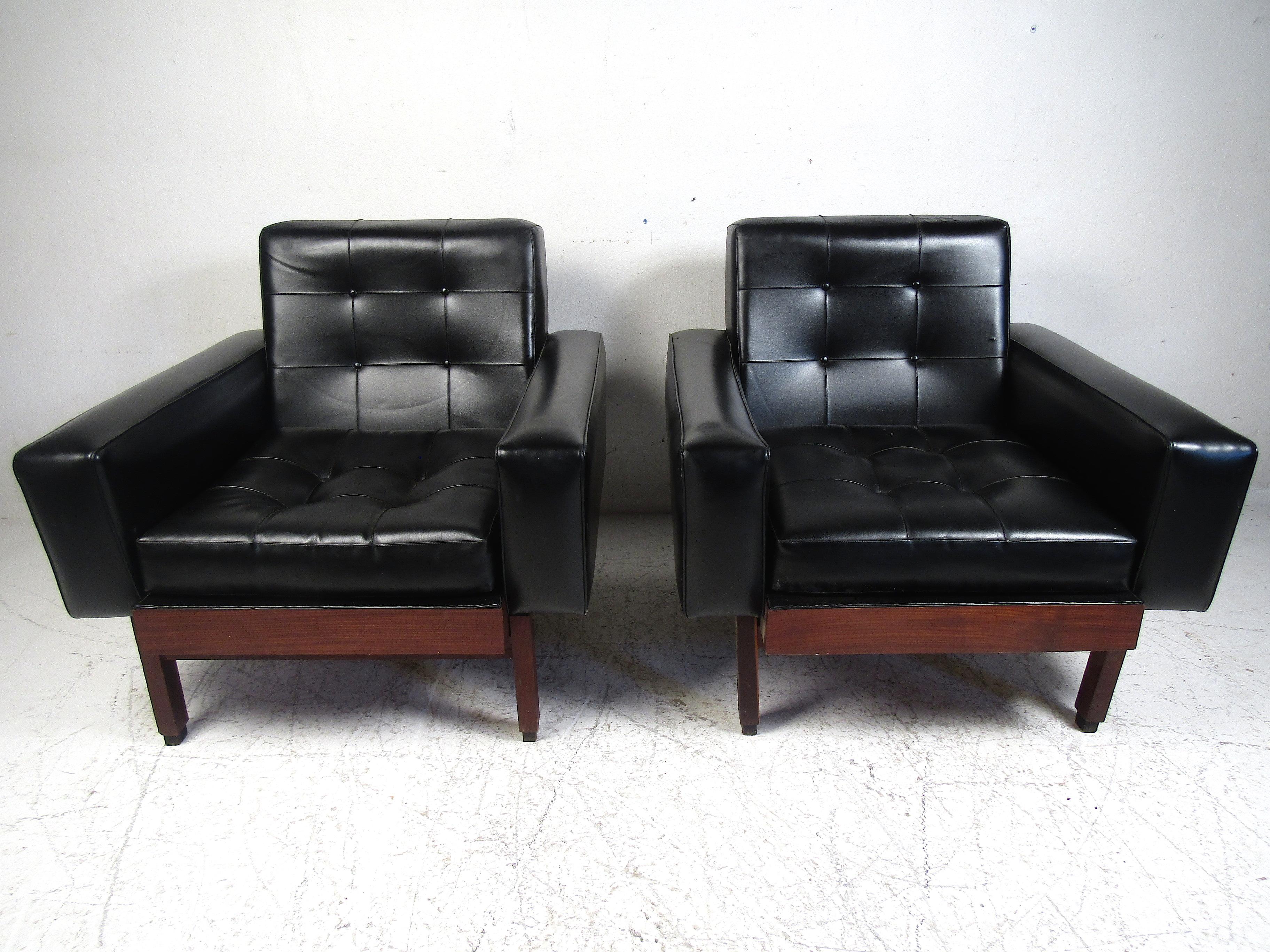 Stylish pair of mid-century lounge chairs. Covered in a vintage black faux-leather upholstery which is secured by decorative nails around the edges. Sure to be a nice fit in any modern interior. Please confirm item location with dealer (NJ or NY).