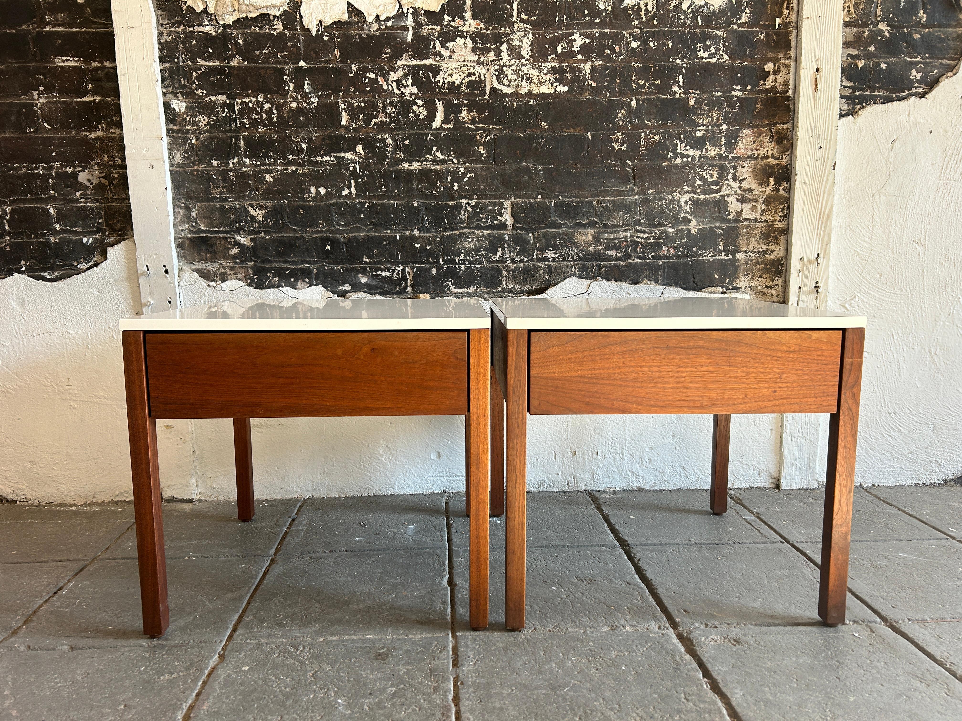 Paire de magnifiques tables de nuit ou tables d'appoint à un tiroir de Florence Knoll. Tables de nuit à un tiroir en noyer avec plateaux en stratifié blanc. Tiroirs en chêne massif avec une seule cloison blanche. Les tiroirs sont équipés de