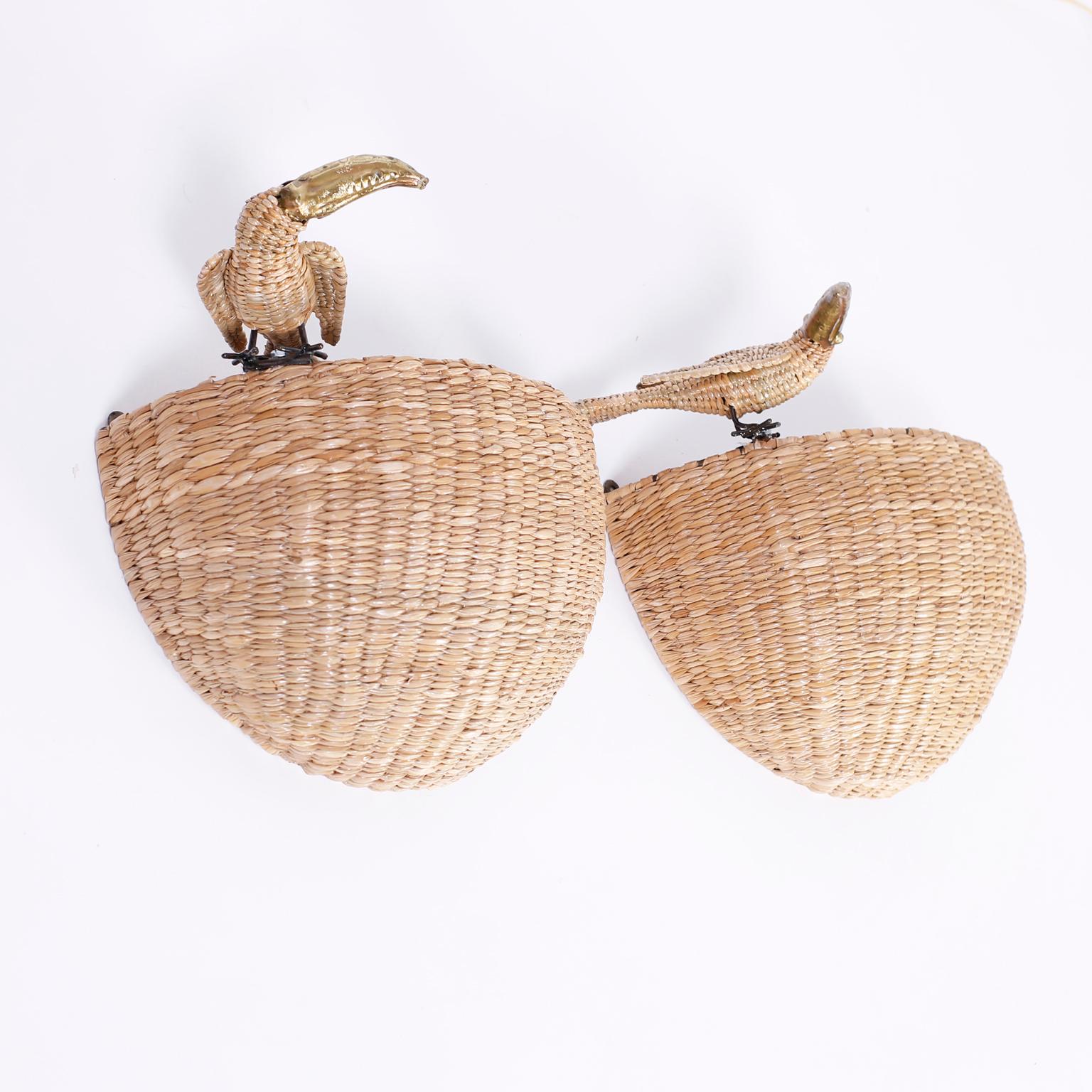 Whimsical wall sconces or torchiere crafted with a metal frame wrapped in reed and having toucans perched at the tops with brass beaks.