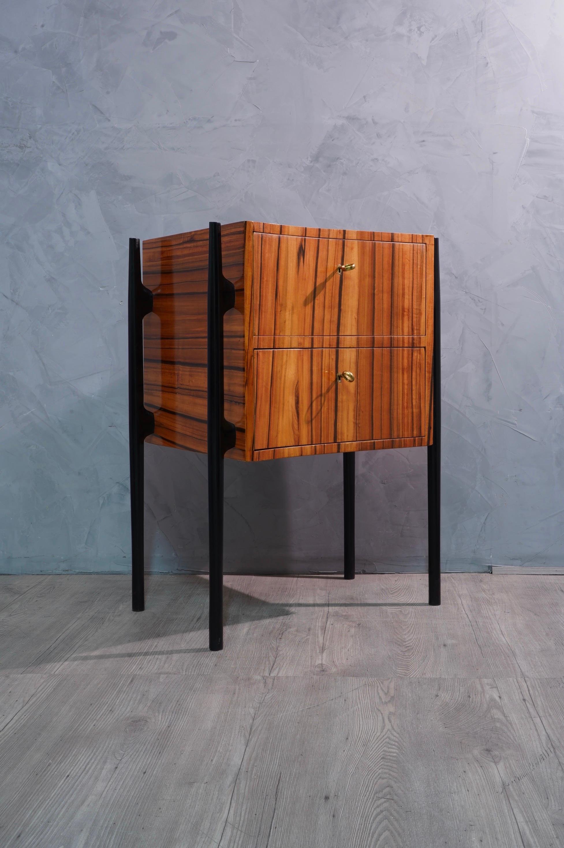 Pair of beautiful bedside tables with a very particular asymmetrical design, made even more eccentric by a very veined cherry wood.

The bedside tables have an asymmetrical wooden body, veneered in cherry wood. They have two drawers, which can be