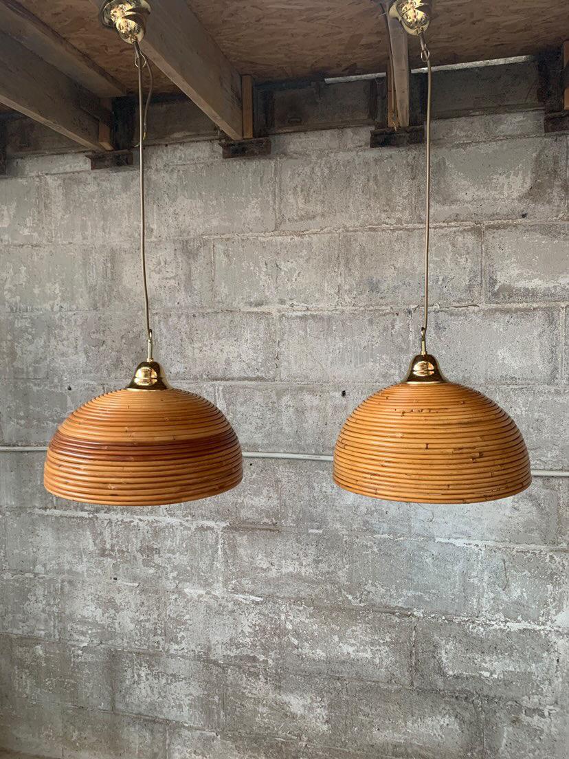Wonderful pair of Italian midcentury pencil reed rattan pendants from the 1970s. This pair has been rewired and as the old brass caps were too far gone they have also been replaced. The natural rattan bamboo varies in colors as can be seen in the